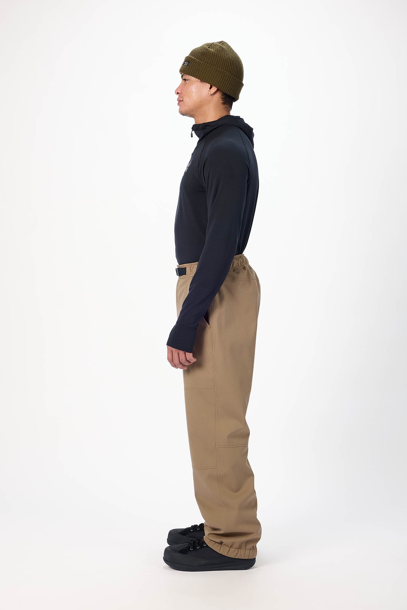 Person wearing a navy jacket, beige pants, and a green beanie on a white background