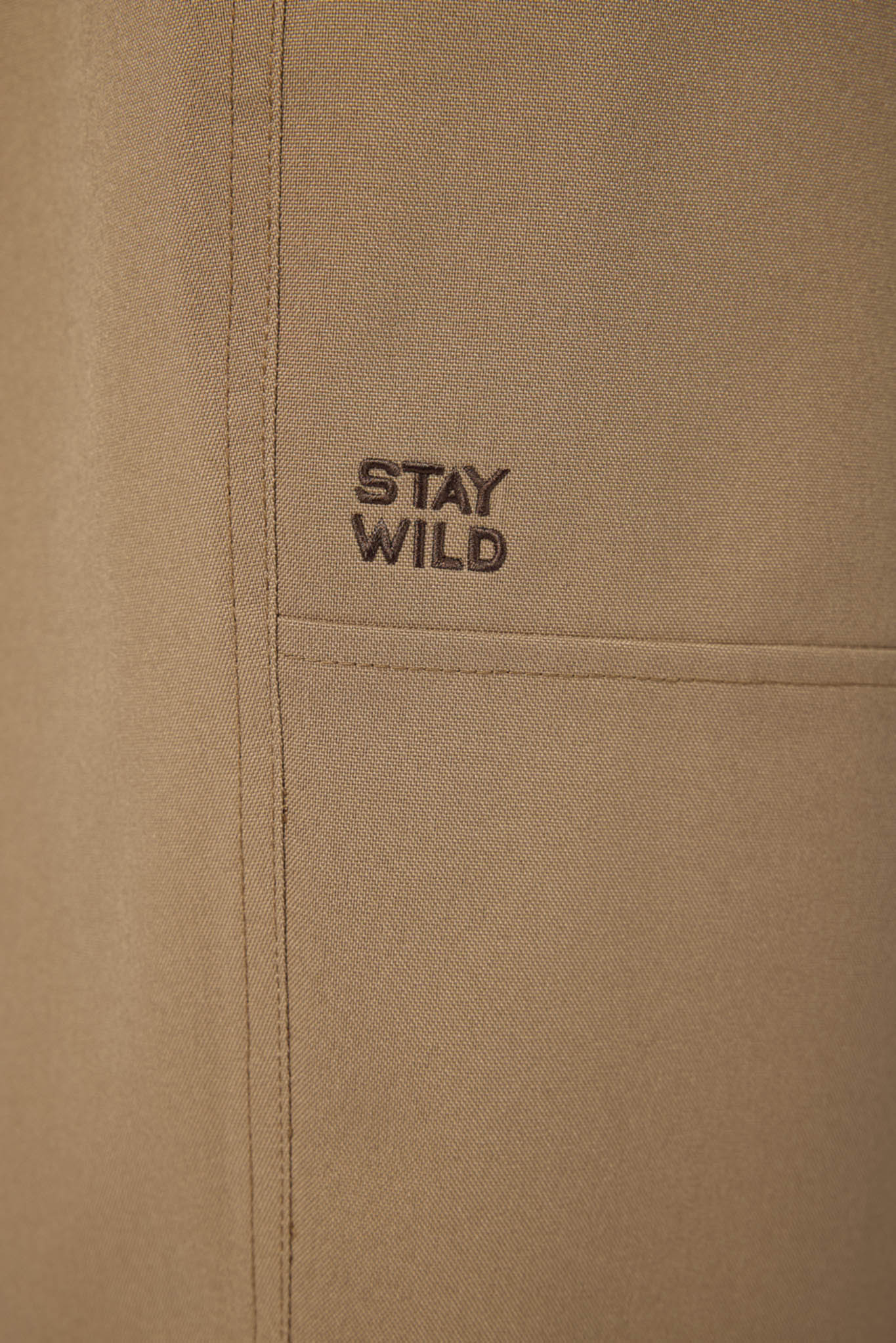 Beige fabric with 'STAY WILD' text embroidered on it