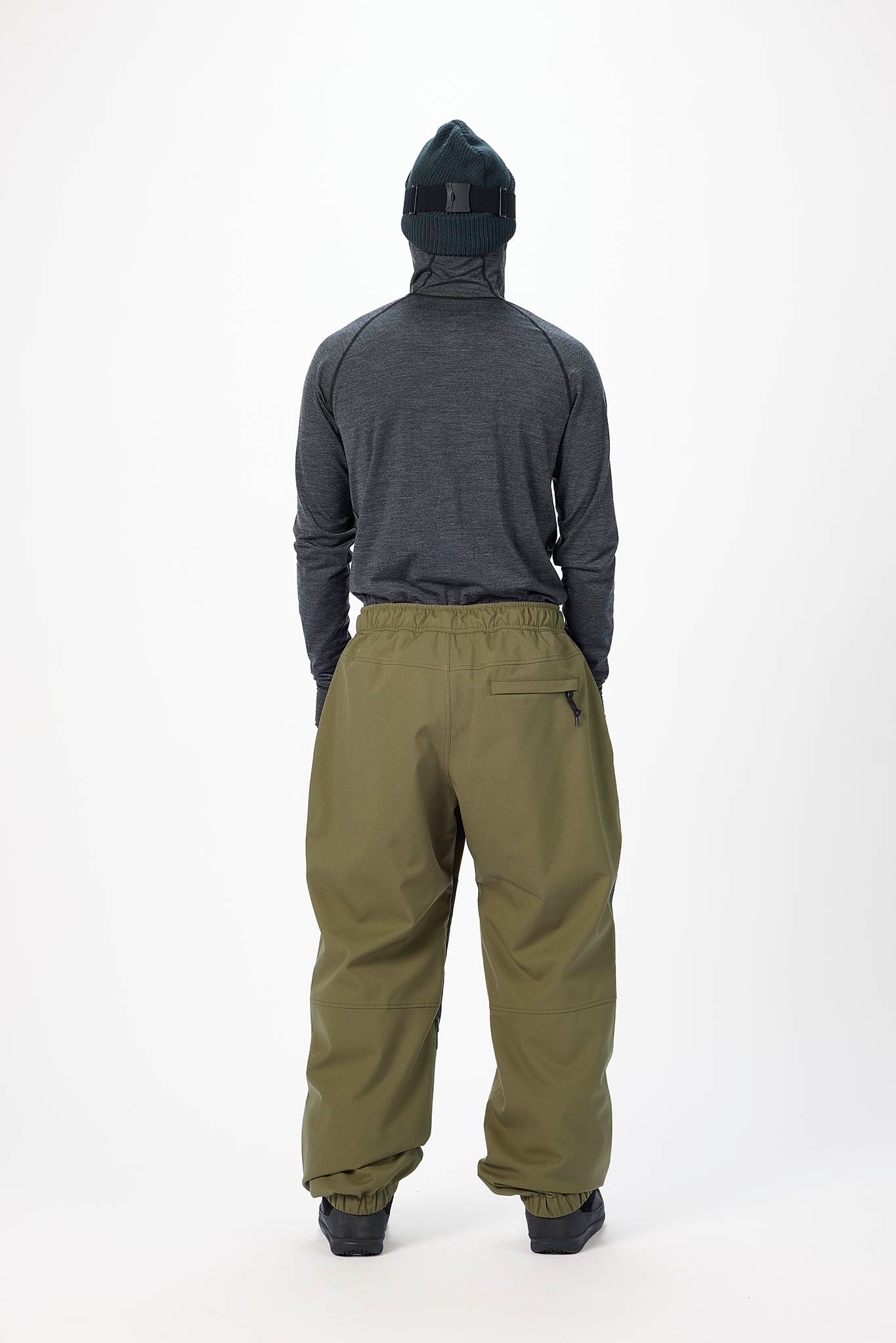 Person wearing a dark gray hoodie and olive green pants on a white background