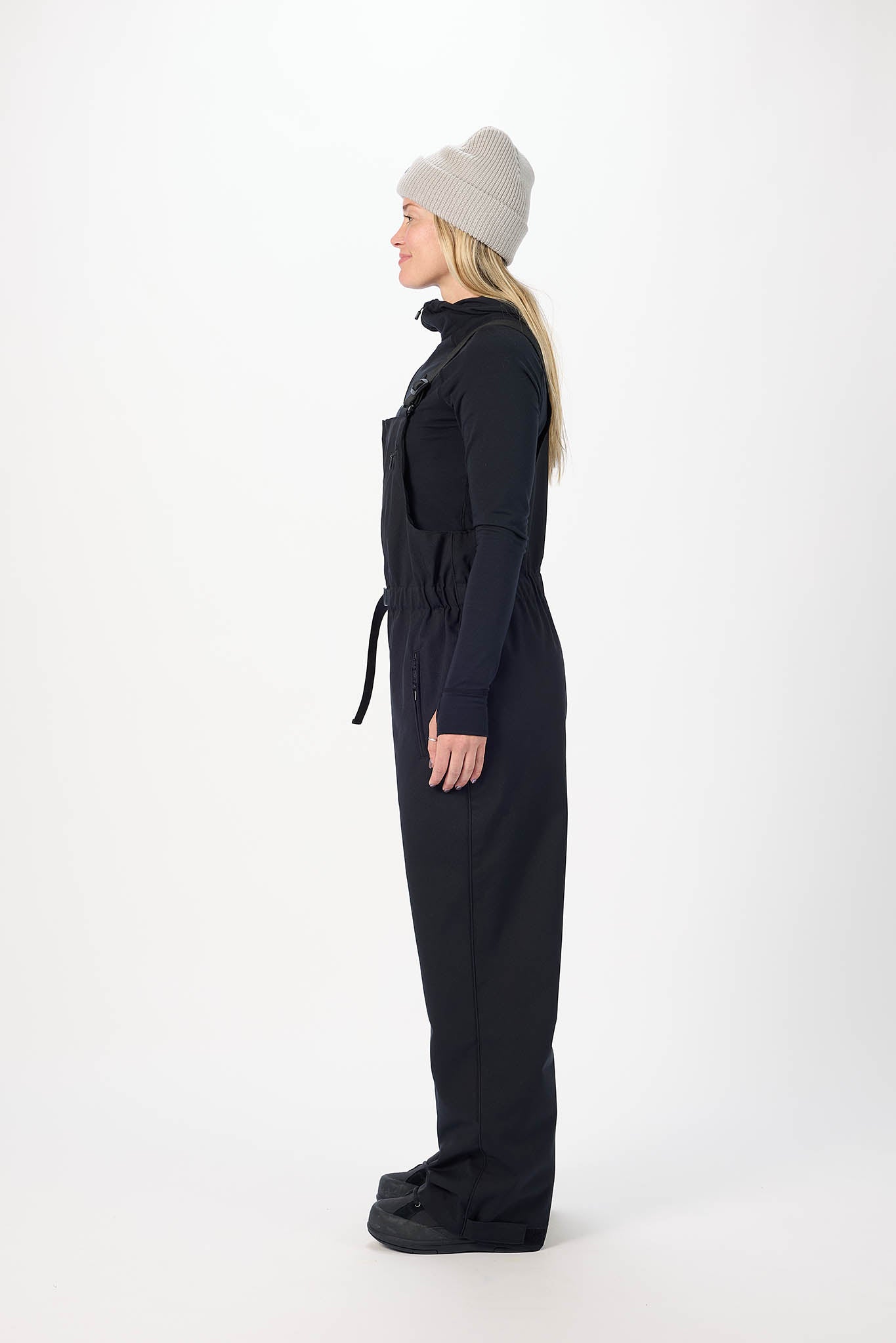 Person wearing a black jumpsuit and gray beanie on a white background