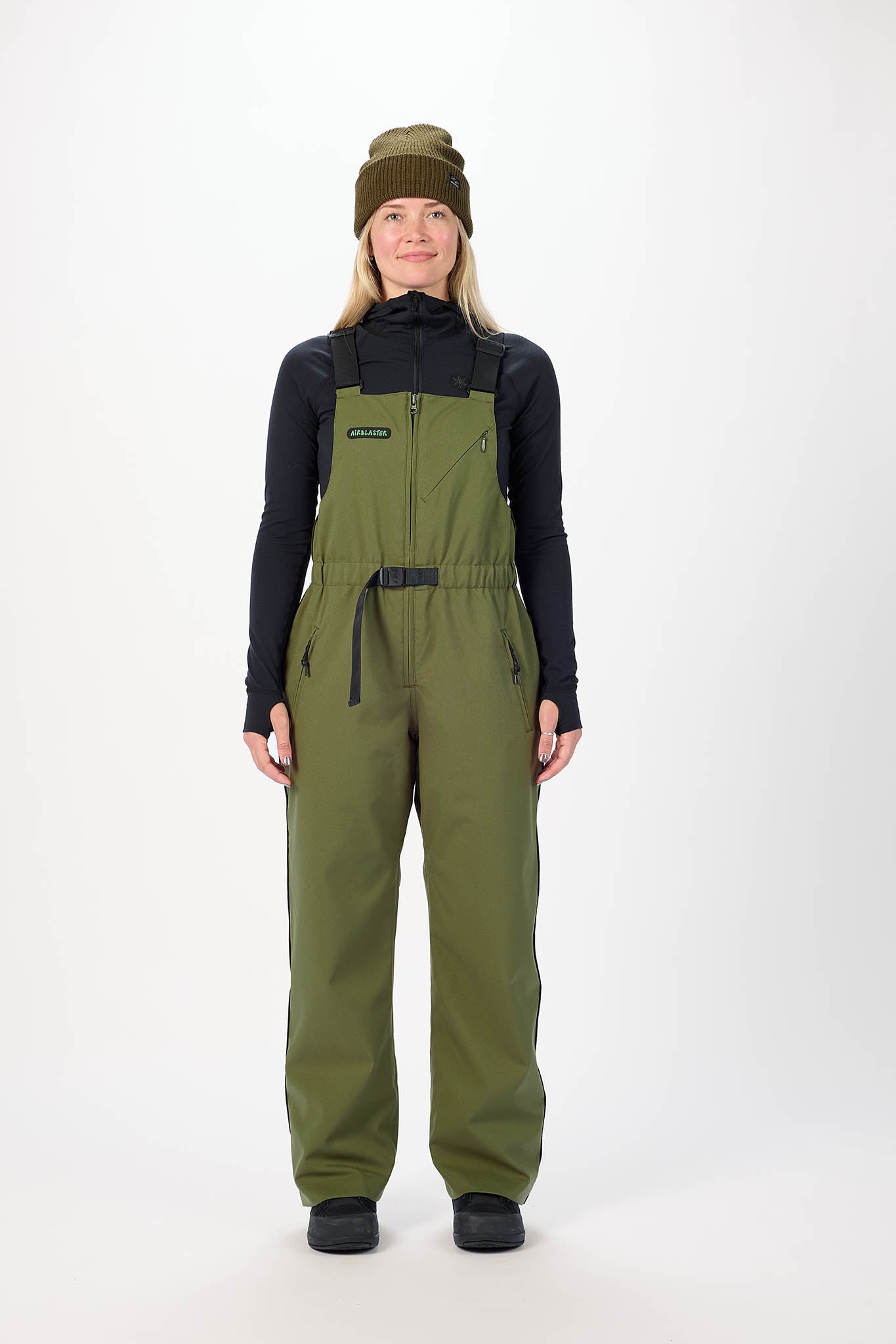 Person wearing green bib overalls and a black jacket on a white background