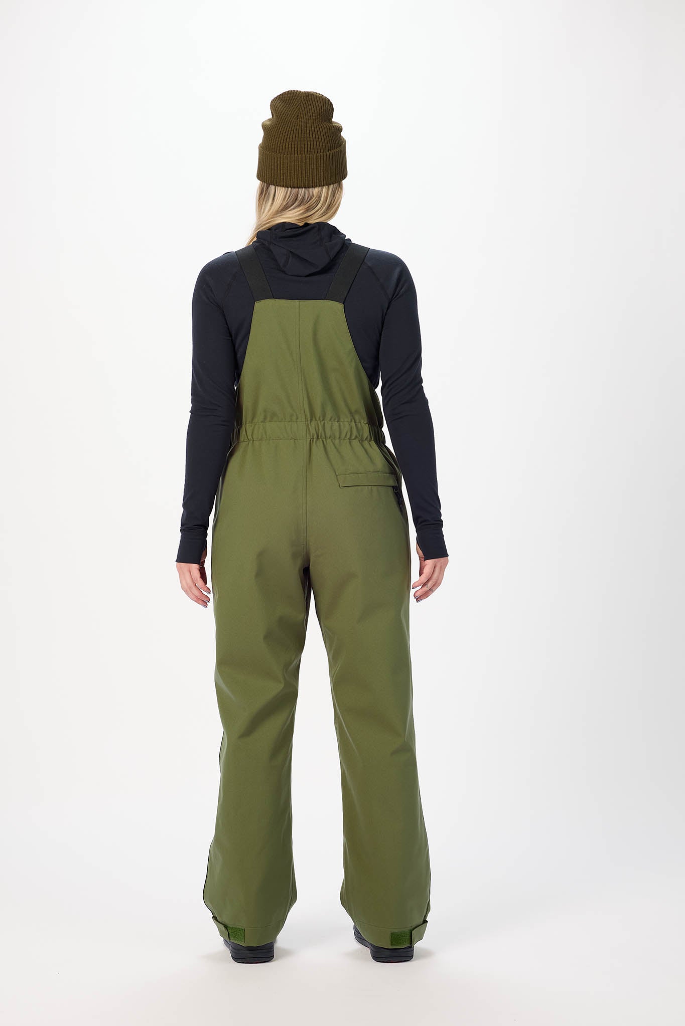 Person wearing green bib overalls on a white background