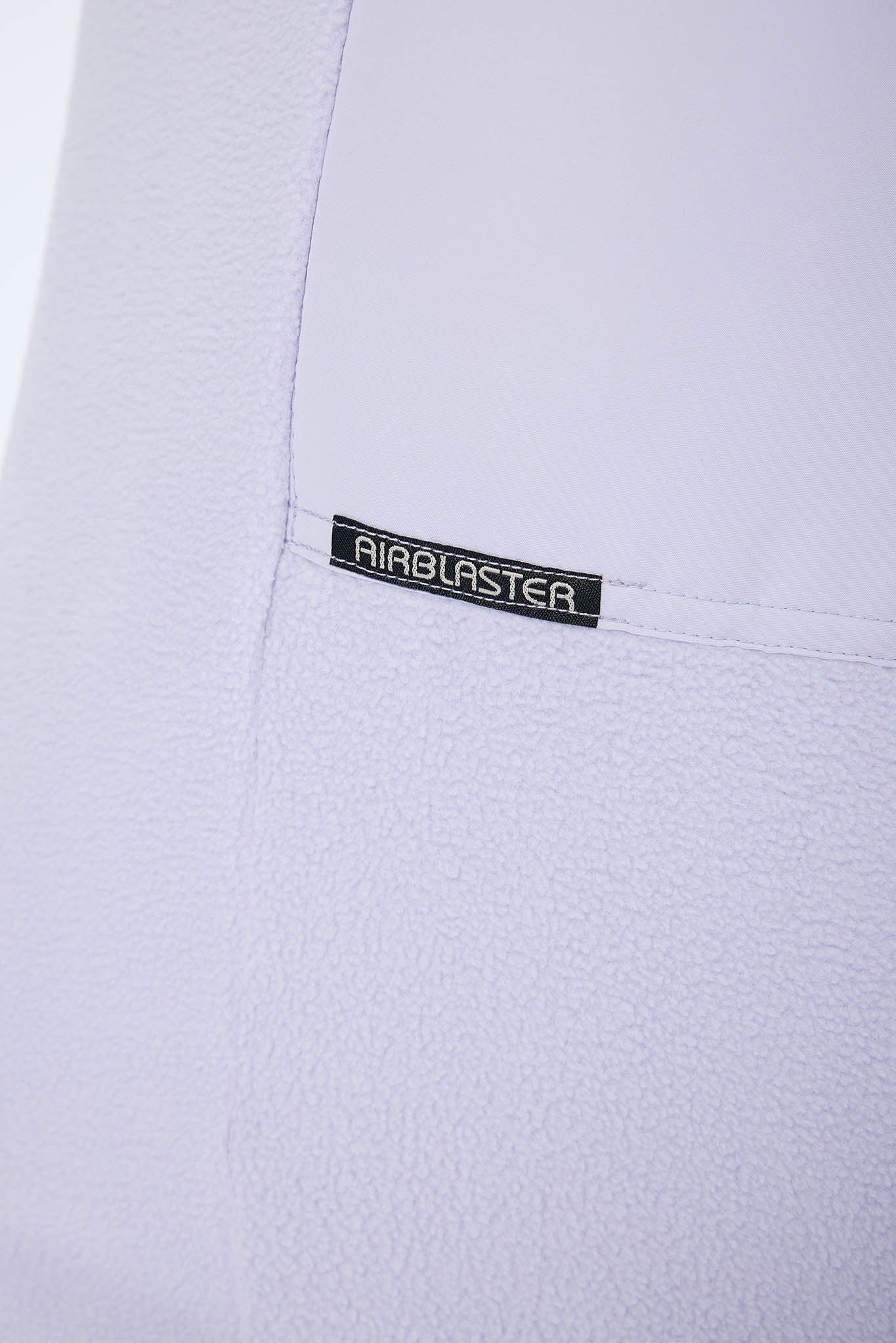 Close-up of a white textured garment with a black rectangular AIRBLASTER logo patch on the chest.