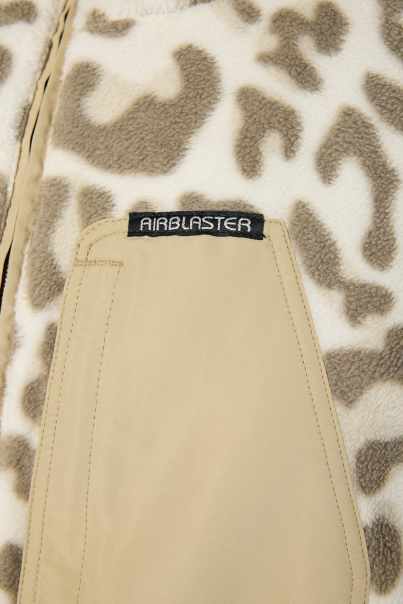 Close-up of a beige Airblaster pocket on a cream and brown leopard-print fleece jacket.