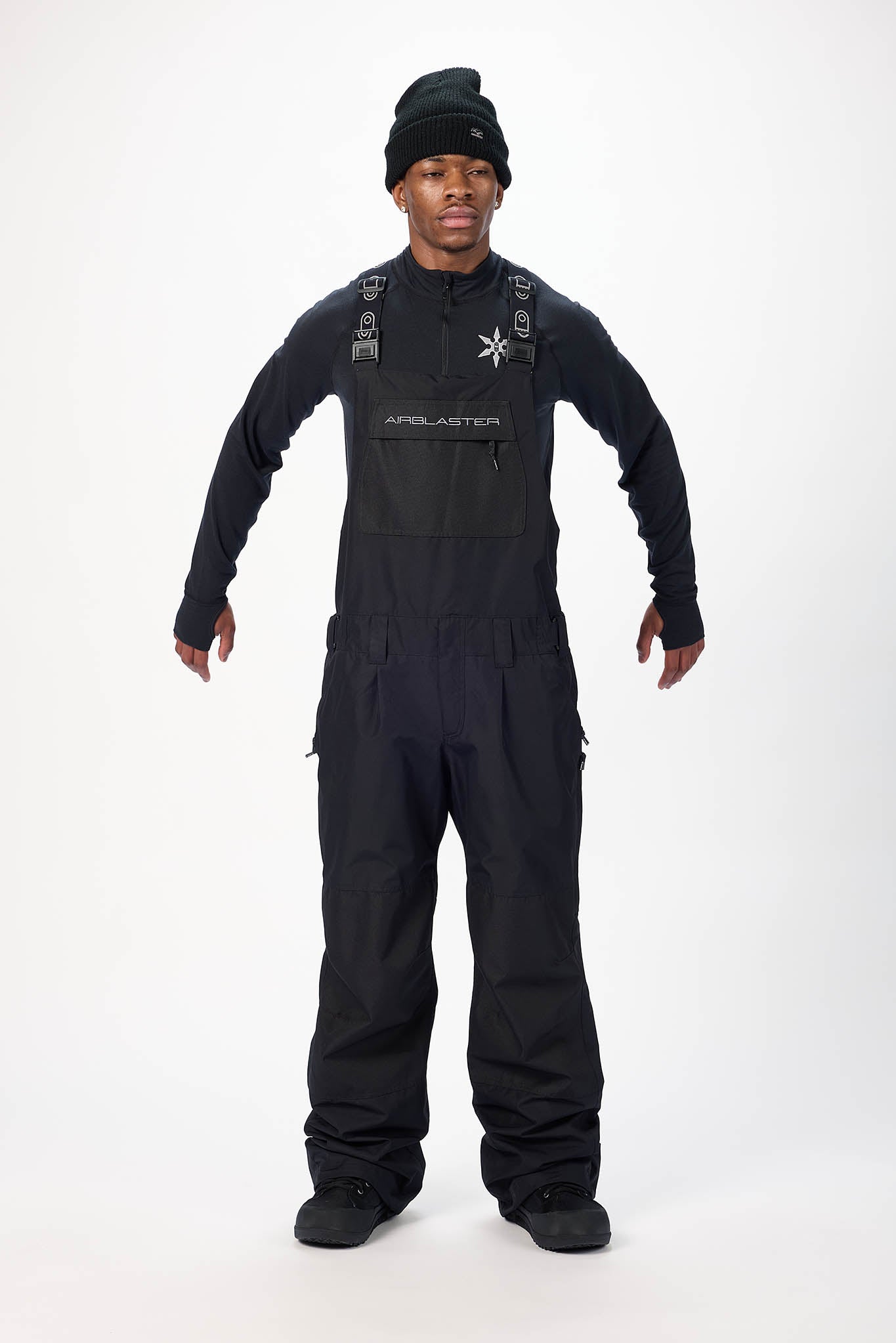 Person wearing a black snow overalls suit with a white background