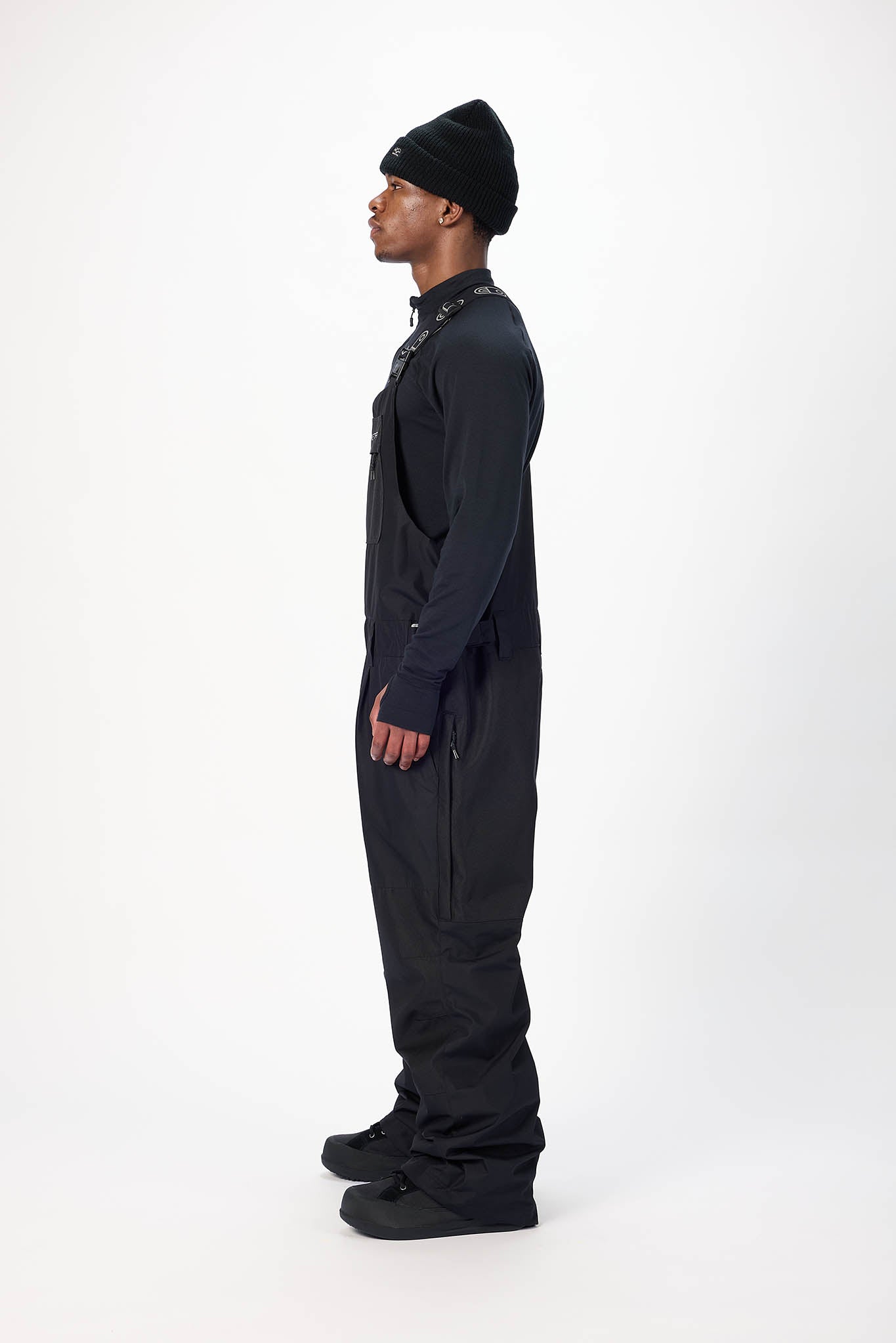 Person wearing a black overalls and beanie on a white background