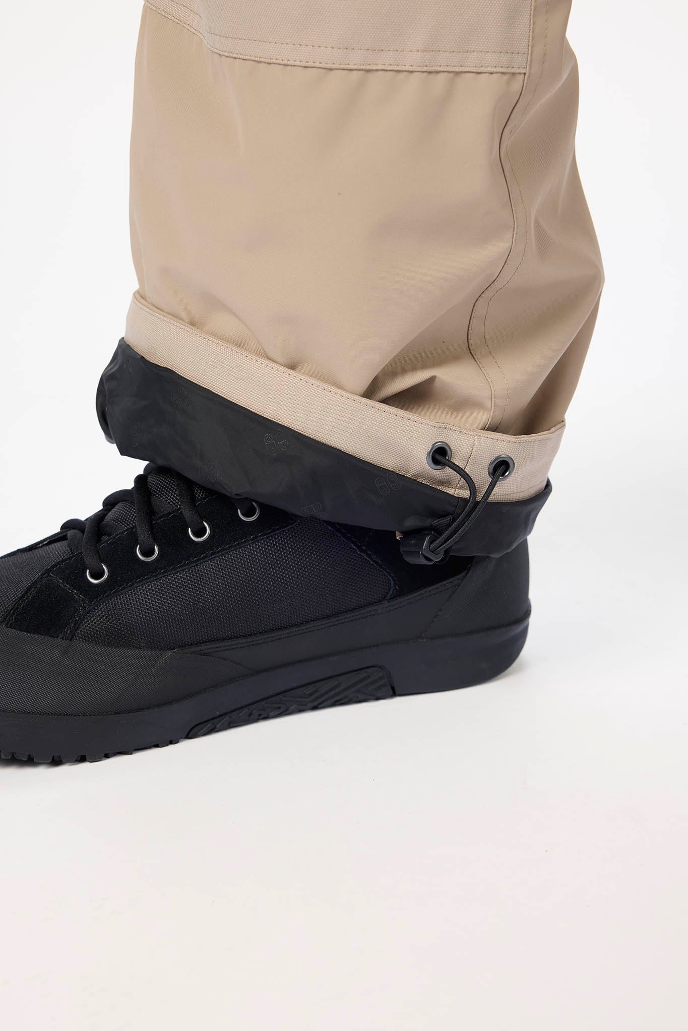 Black boot with beige pants on a white background