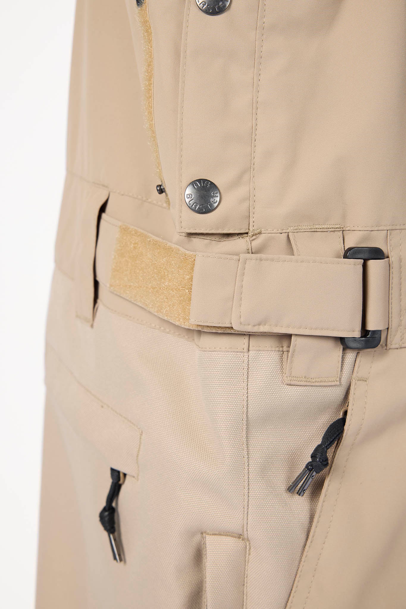 Close-up of beige pants with zippers and buttons on a white background