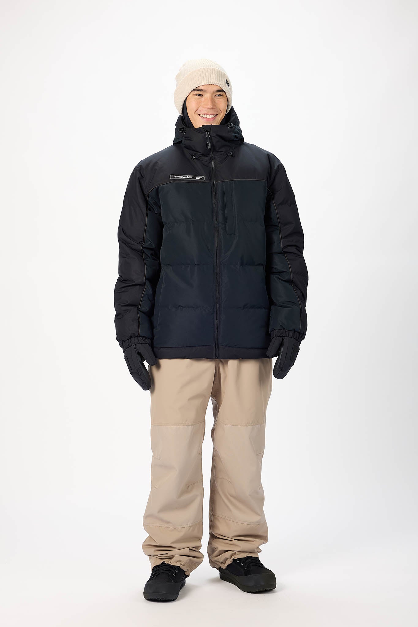 Person wearing a black jacket and beige pants on a white background