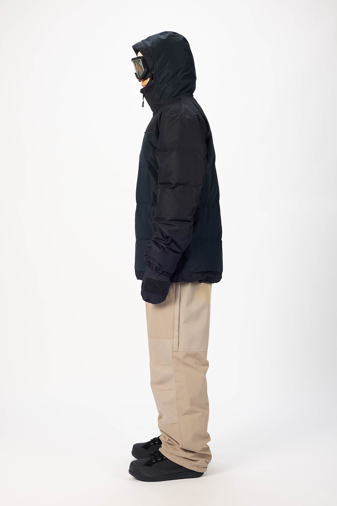 Person wearing a black jacket, beige pants, and black shoes on a white background