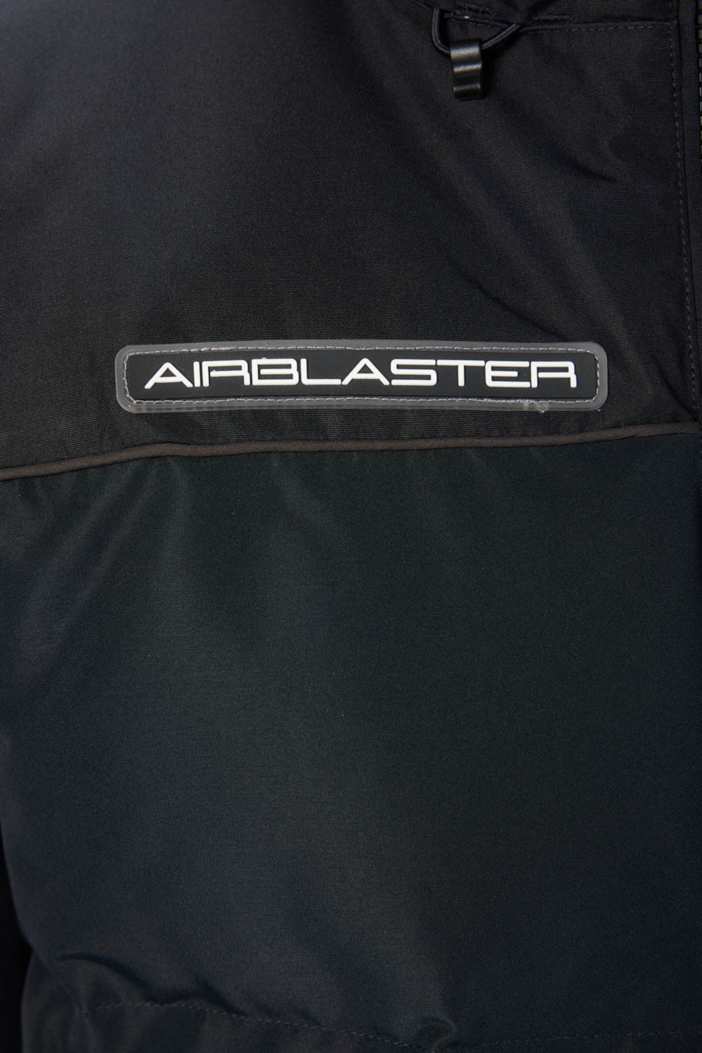 Close-up of a black jacket with 'Airblaster' logo on a dark background