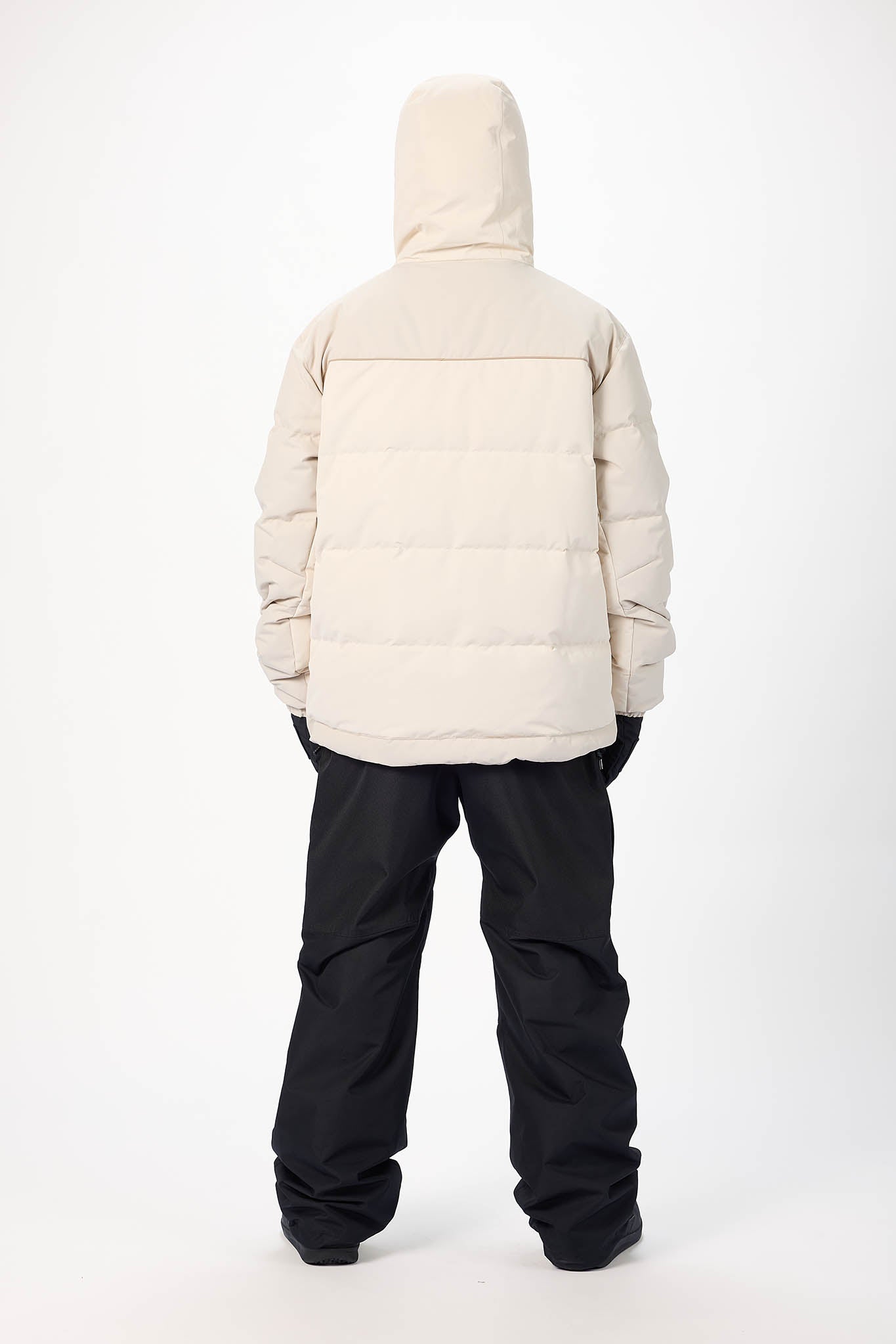 Person wearing a beige puffer jacket and black pants on a white background