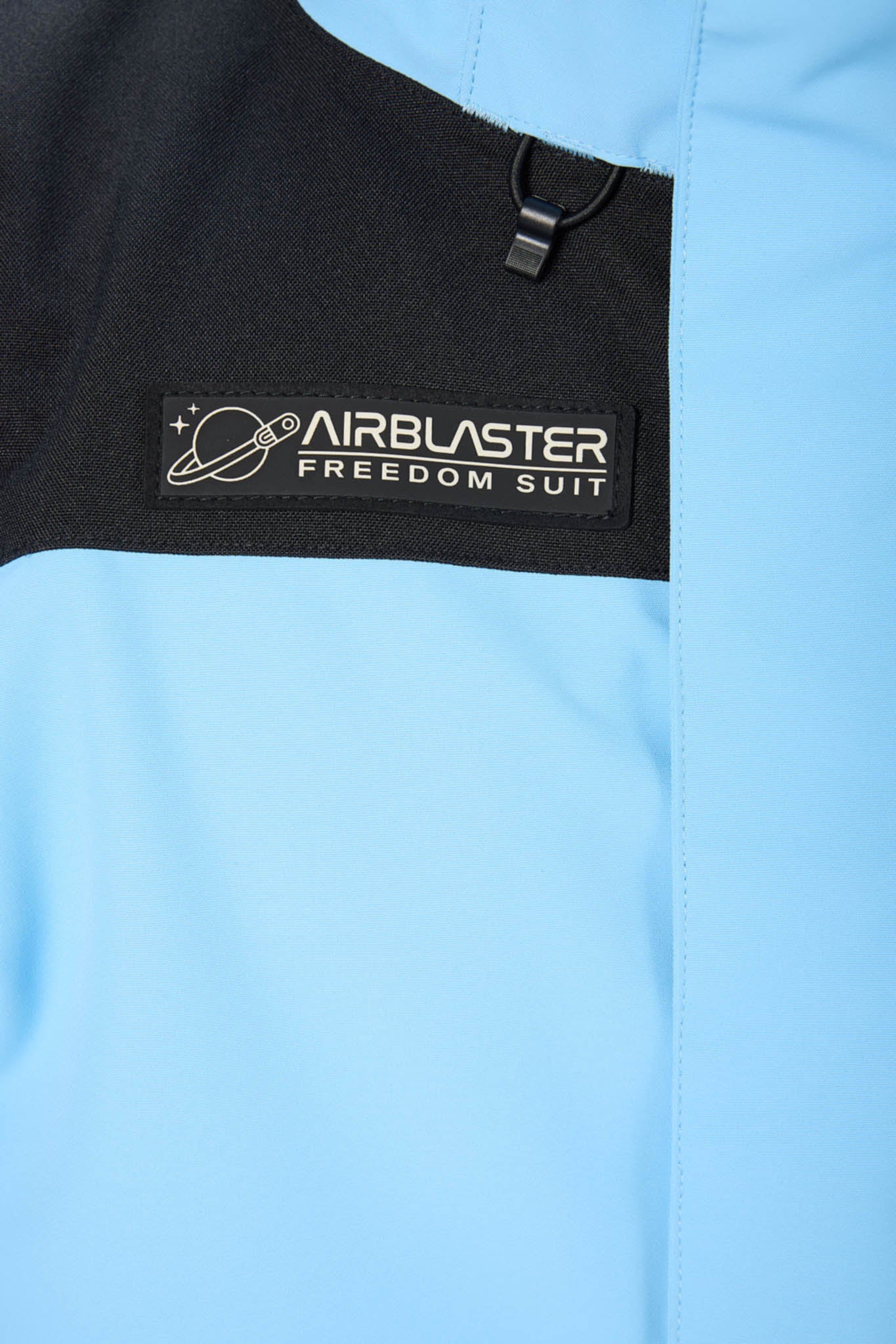 Close-up of a blue jacket with an Airblaster Freedom Suit logo on a black patch.