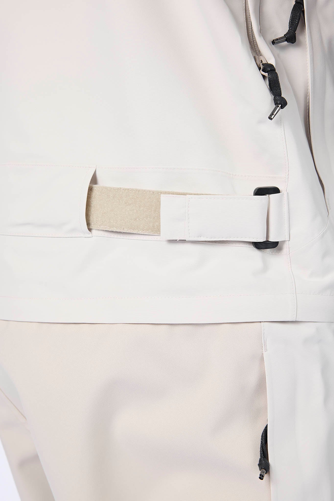 Close-up of a white jacket with a beige strap and black buckle on a light gray background