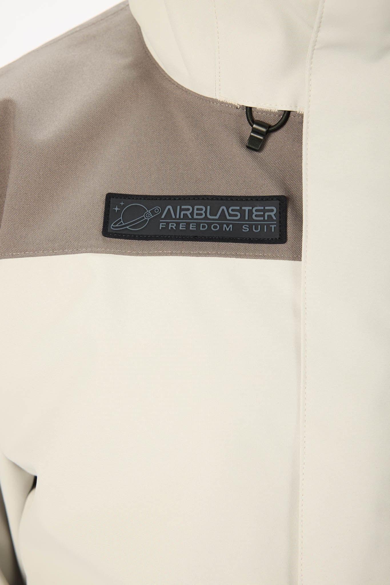 Close-up of a beige jacket with an Airblaster Freedom Suit logo on a white background
