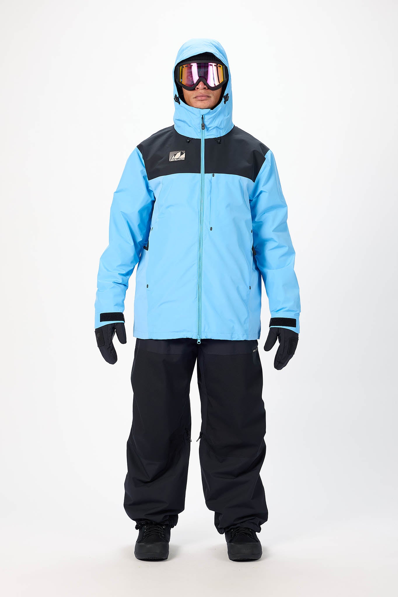 Person wearing a blue and black snowsuit with goggles on a white background