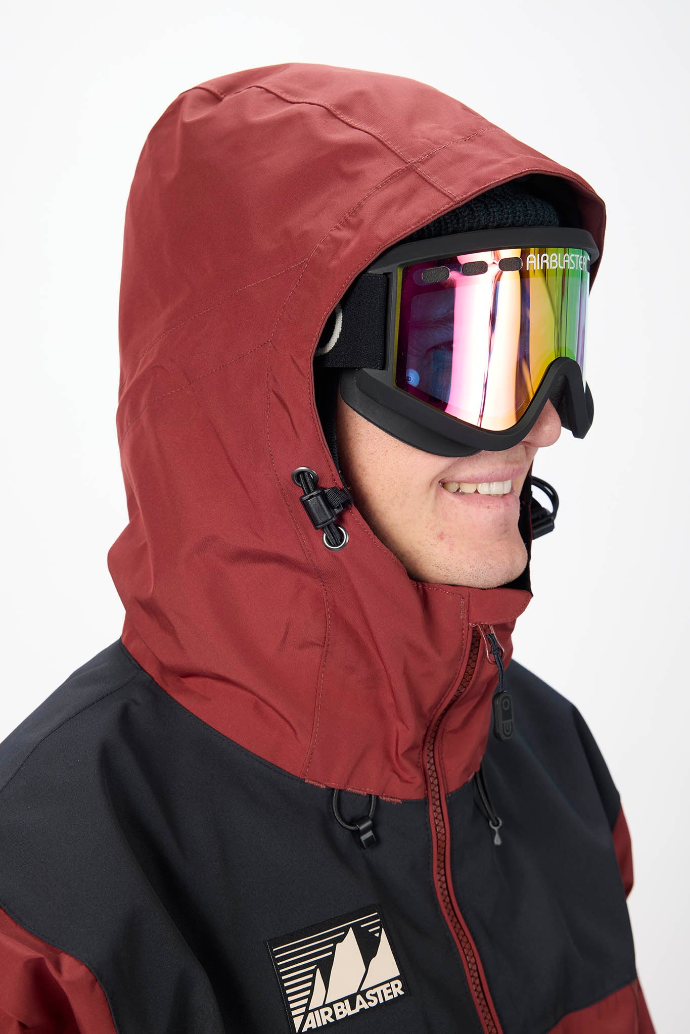 Person wearing a red hooded jacket with a colorful ski mask on a white background.