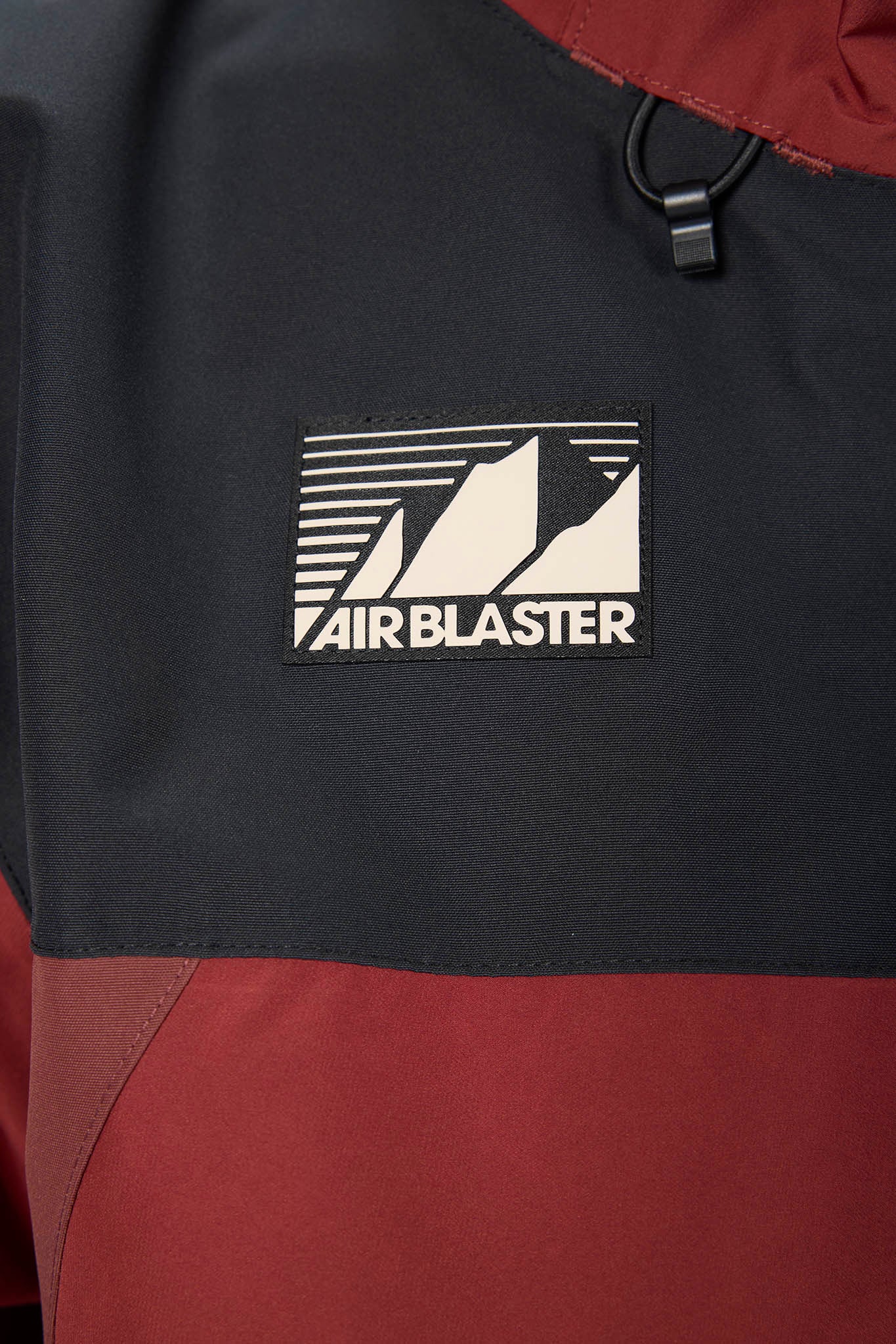 Close-up of a jacket with an 'Airblaster' logo on a black and red background
