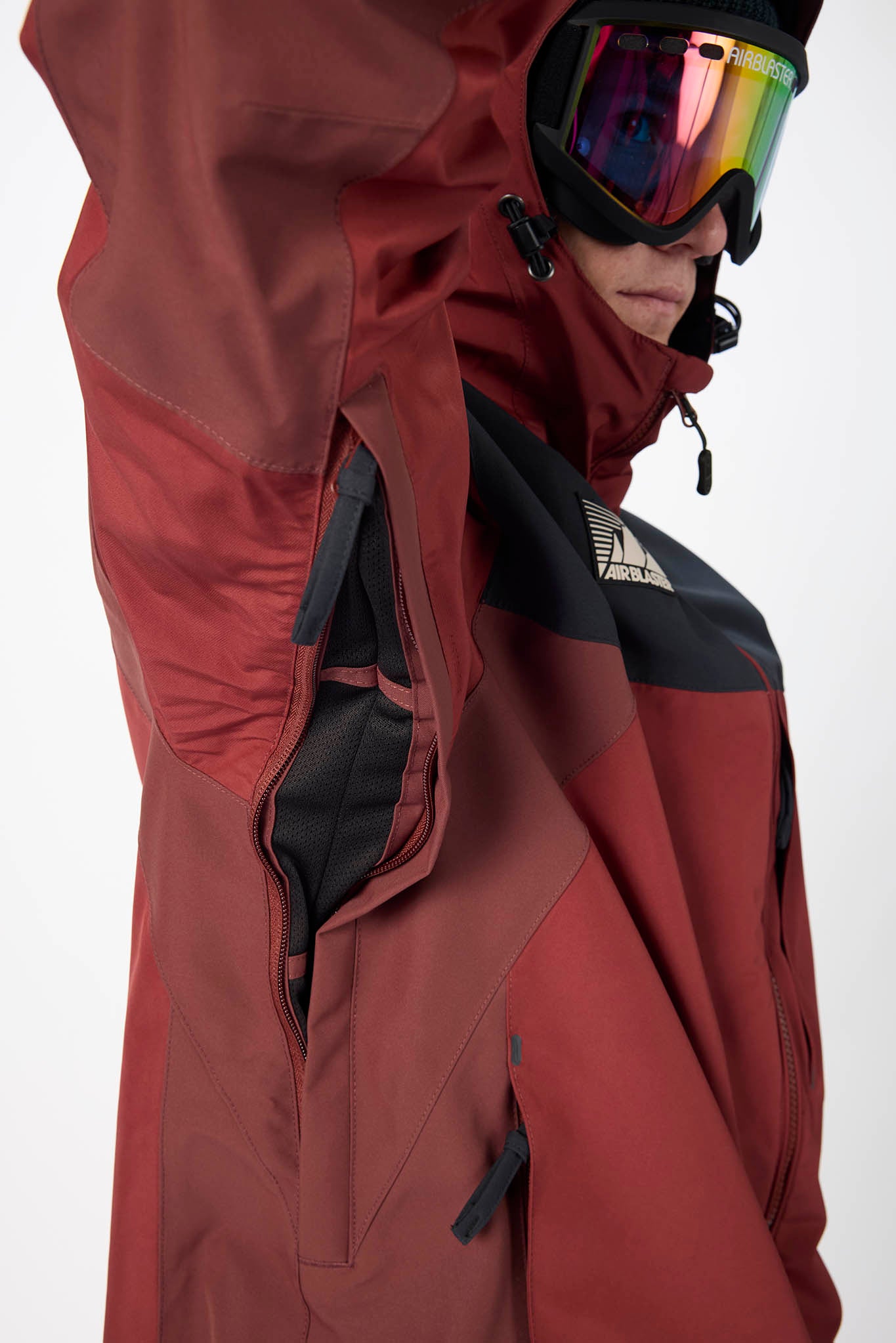 Person wearing a red and black jacket with a hood, standing against a white background