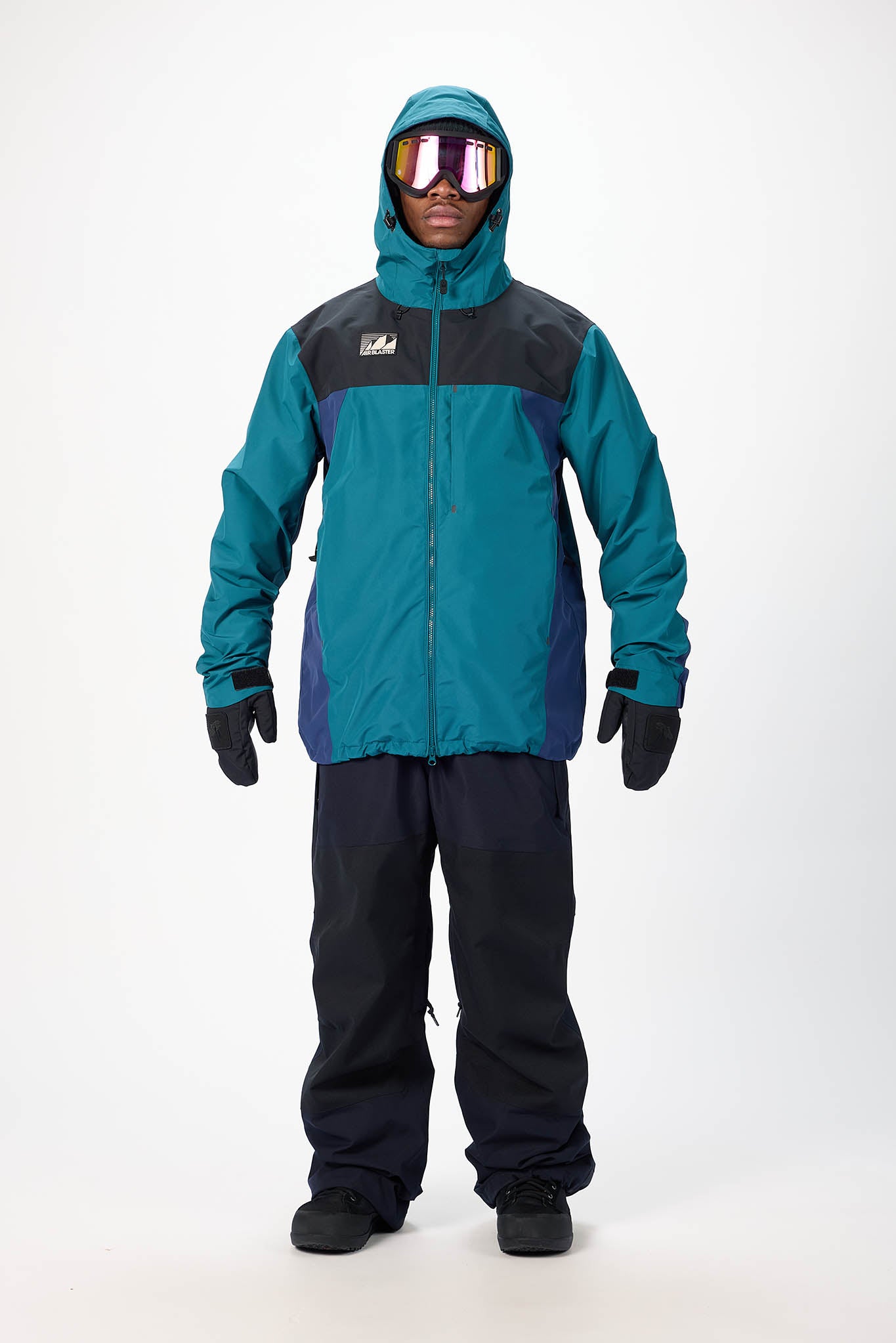 Person wearing a teal and black snowsuit with goggles on a white background