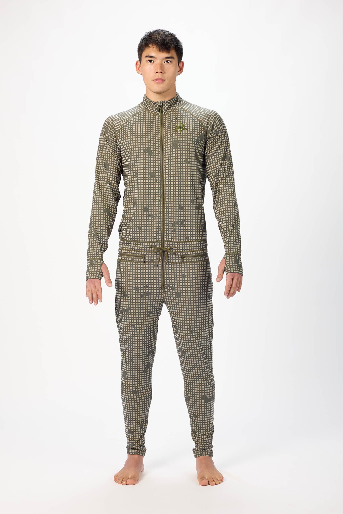 A man modeling a olive grid like pattern full-zip athletic onesie with a small white logo on the left chest, standing against a plain white studio background.