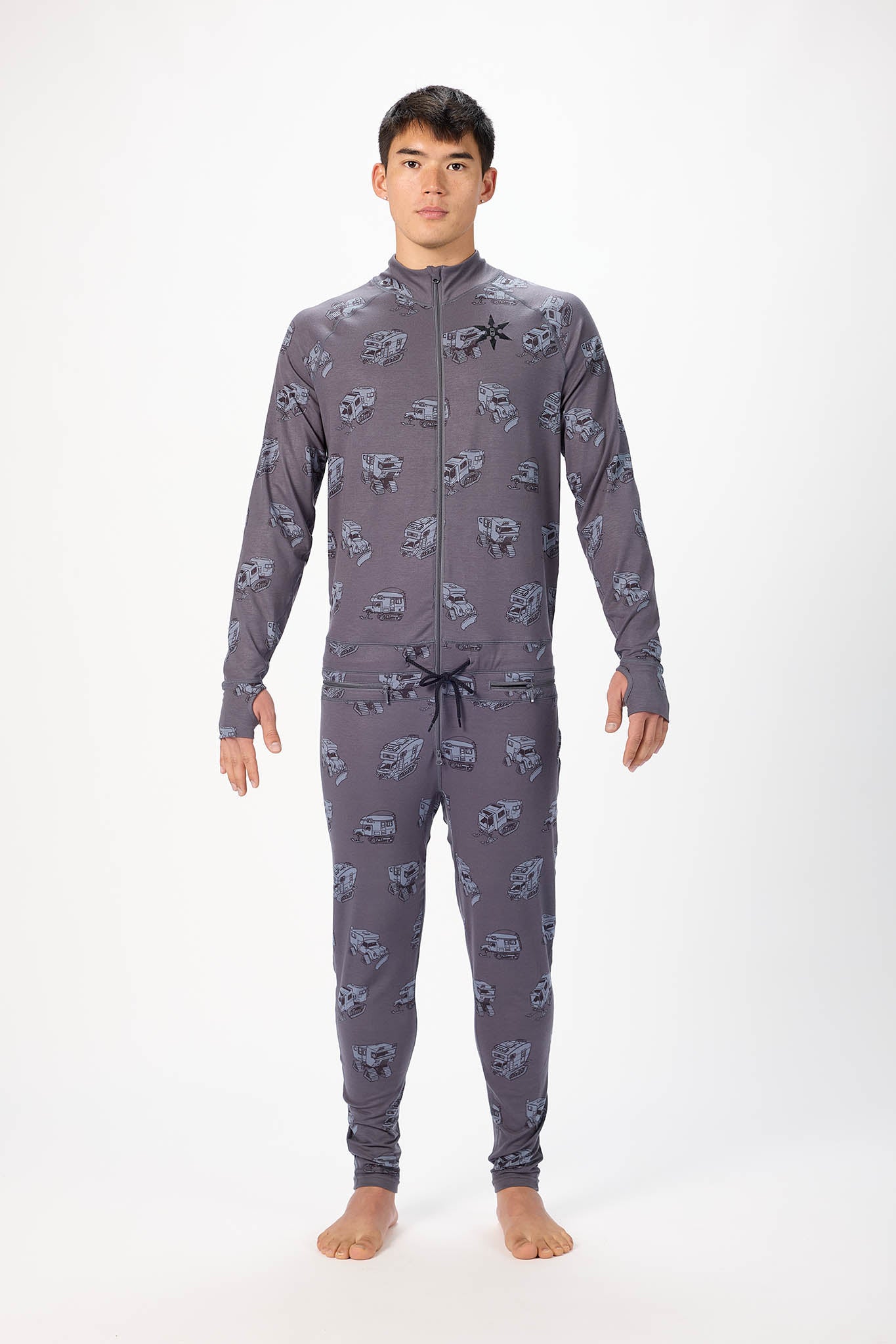 A man modeling a grey pick up truck like pattern full-zip athletic onesie with a small white logo on the left chest, standing against a plain white studio background.