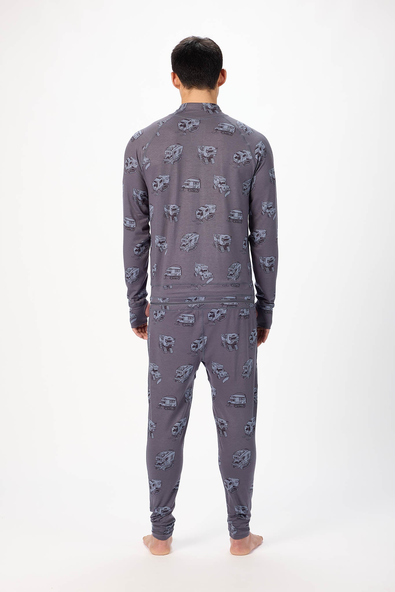 viewed from behind A man modeling a grey pick up truck like pattern full-zip athletic onesie with a small white logo on the left chest, standing against a plain white studio background.