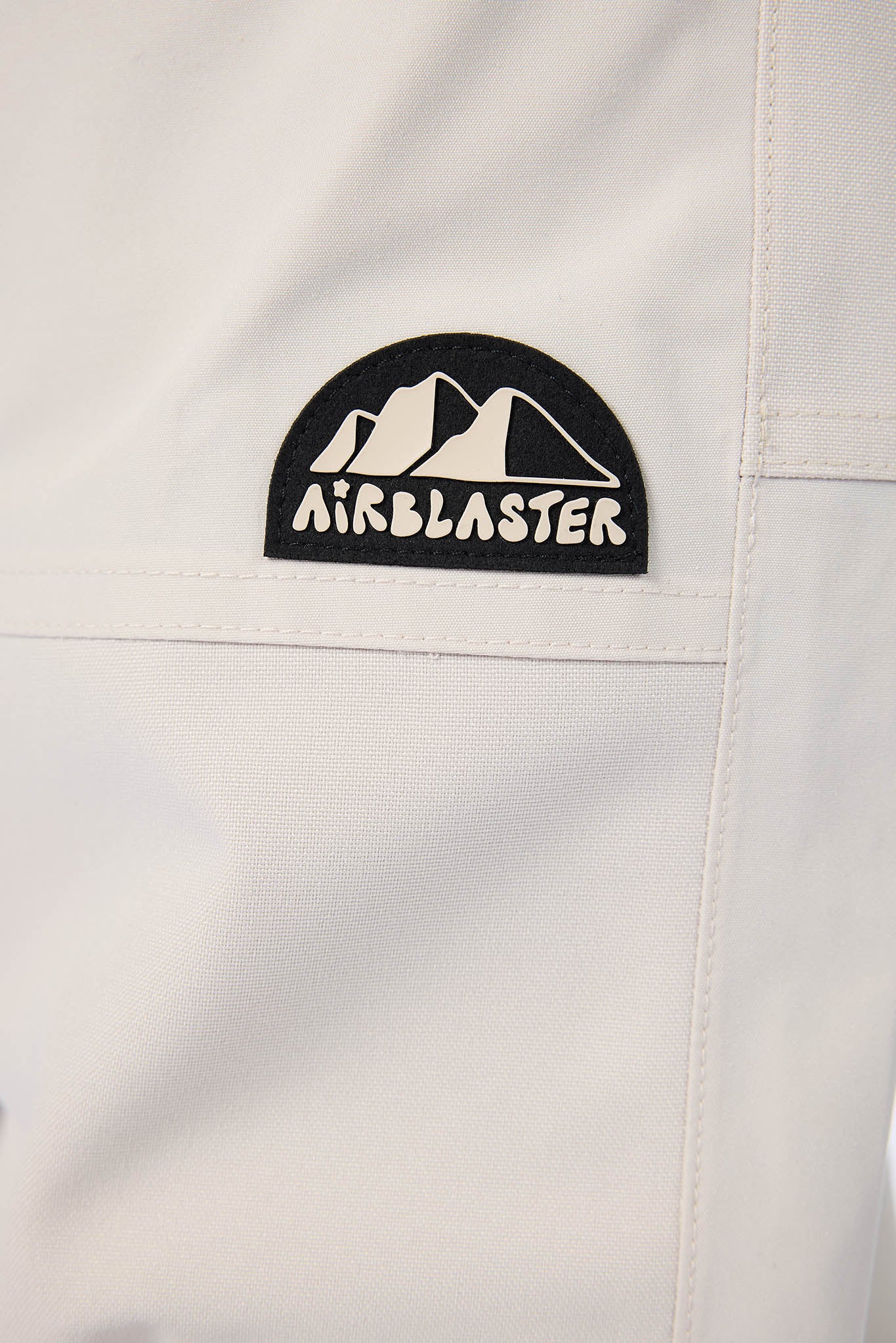 Close-up of a white jacket with an Airblaster logo on a light gray background