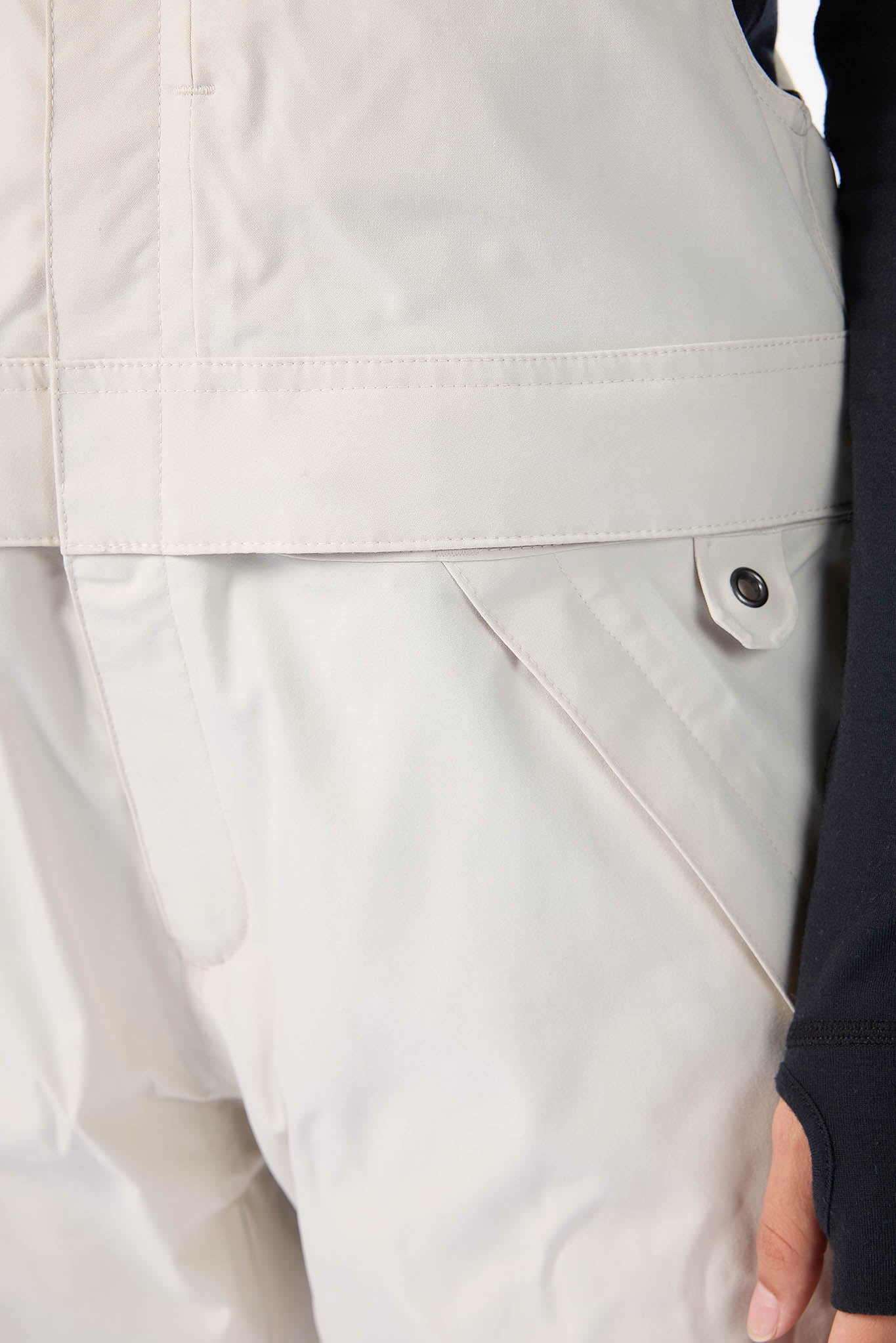 Close-up of beige pants with a button, worn by a person.