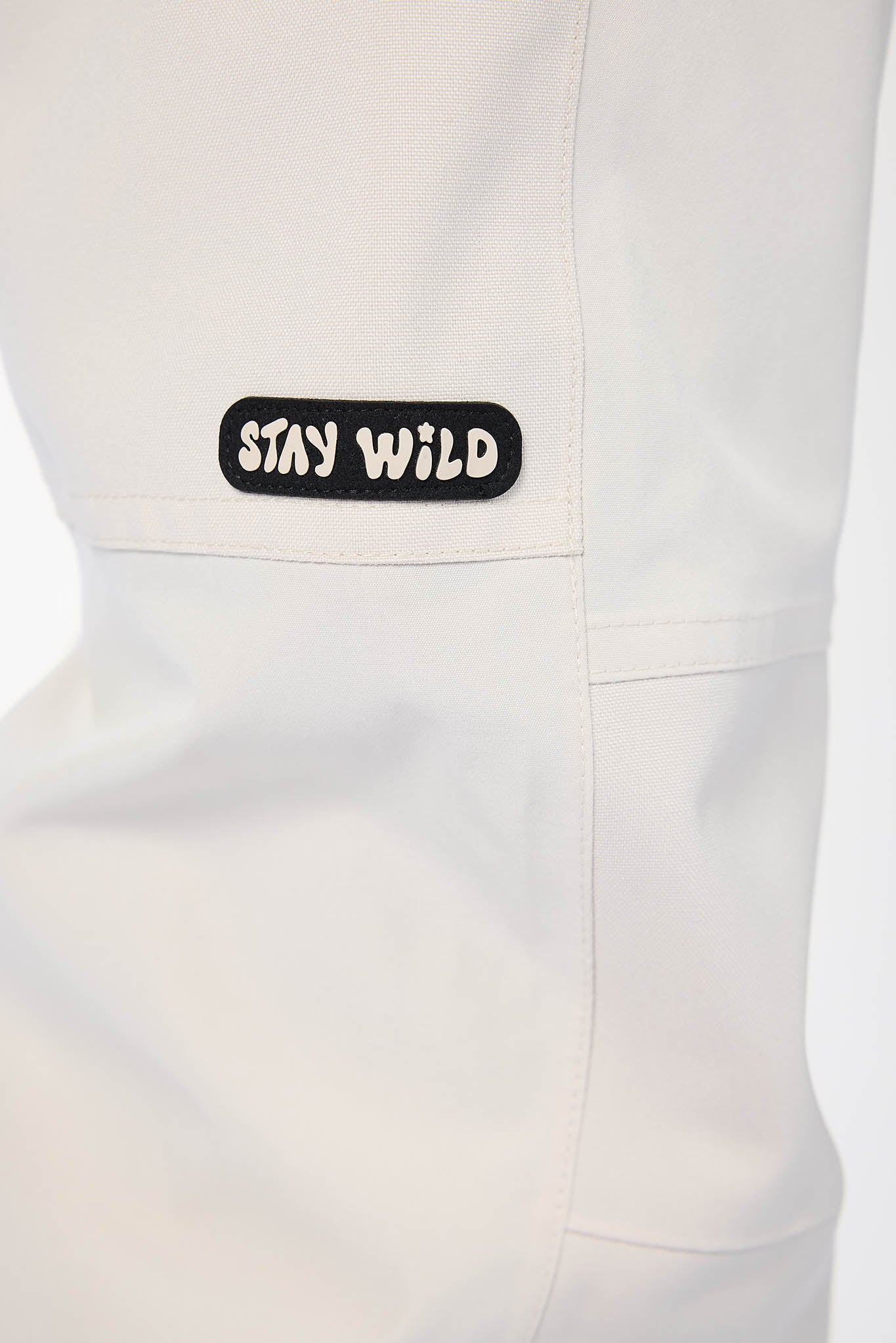 White apron with 'Stay Wild' patch on a white background