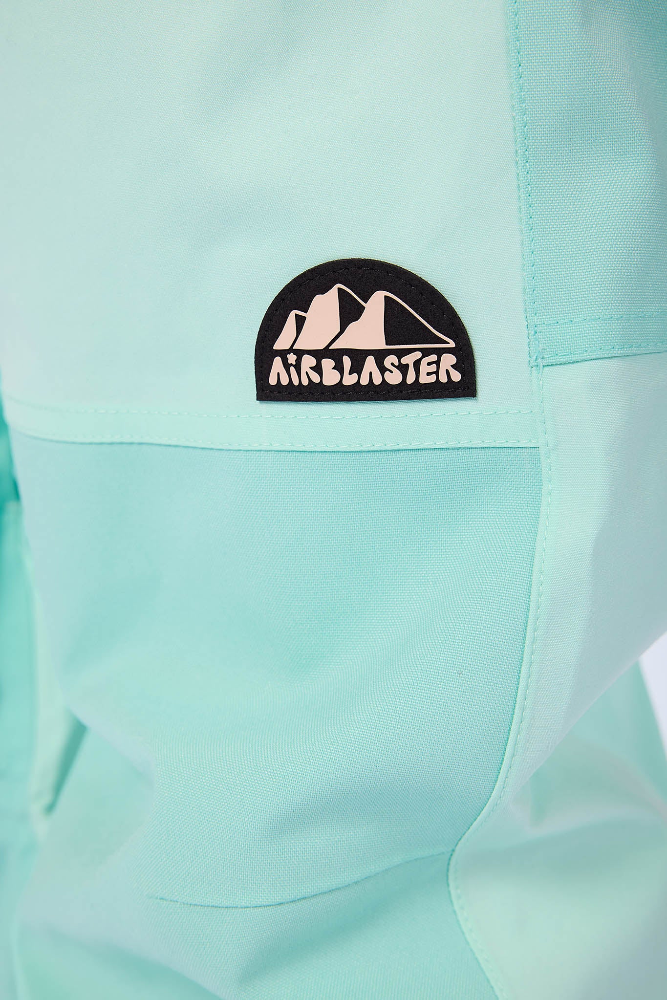 Close-up of a teal jacket with an Airblaster logo patch.