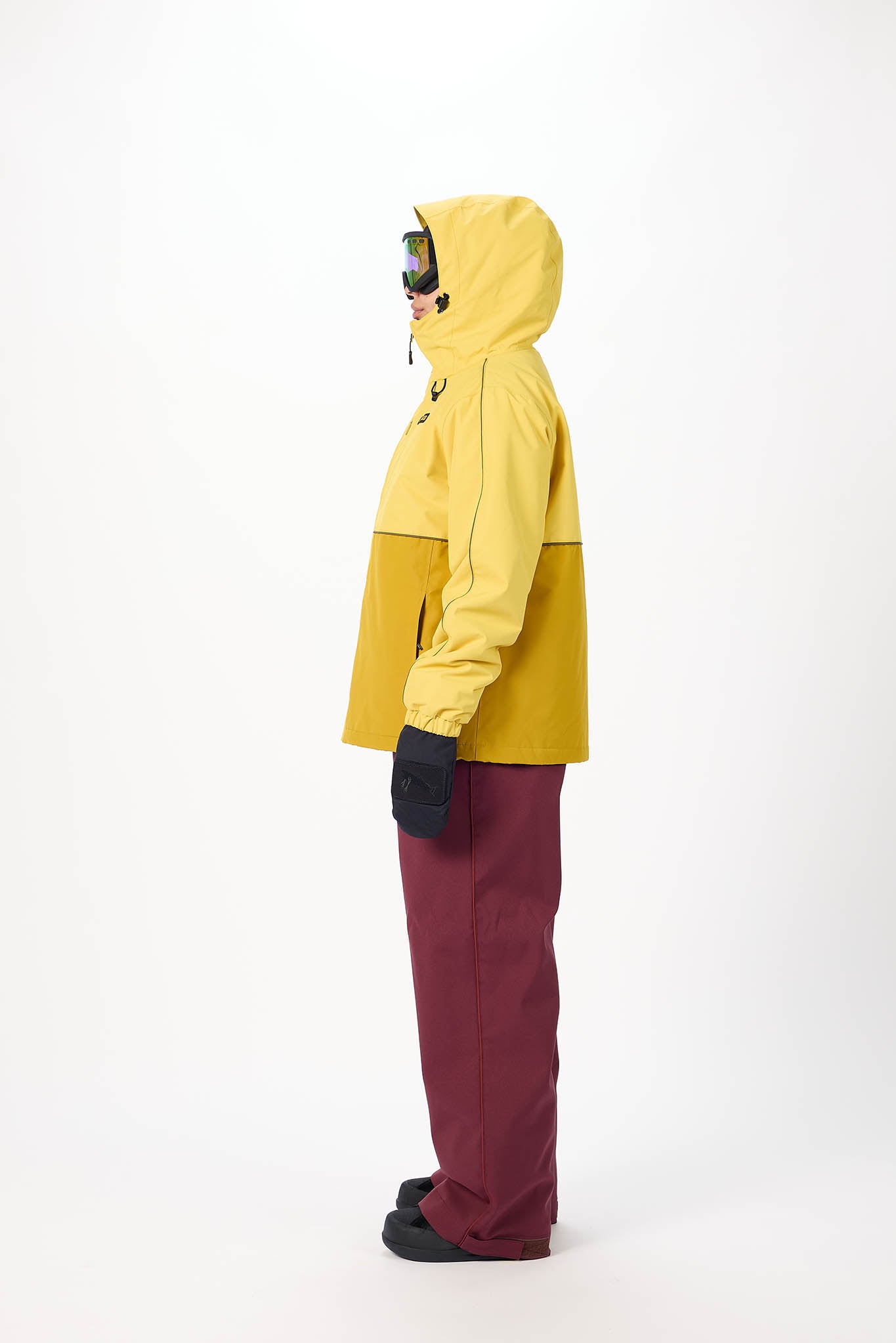 Person wearing a yellow jacket and maroon pants on a white background