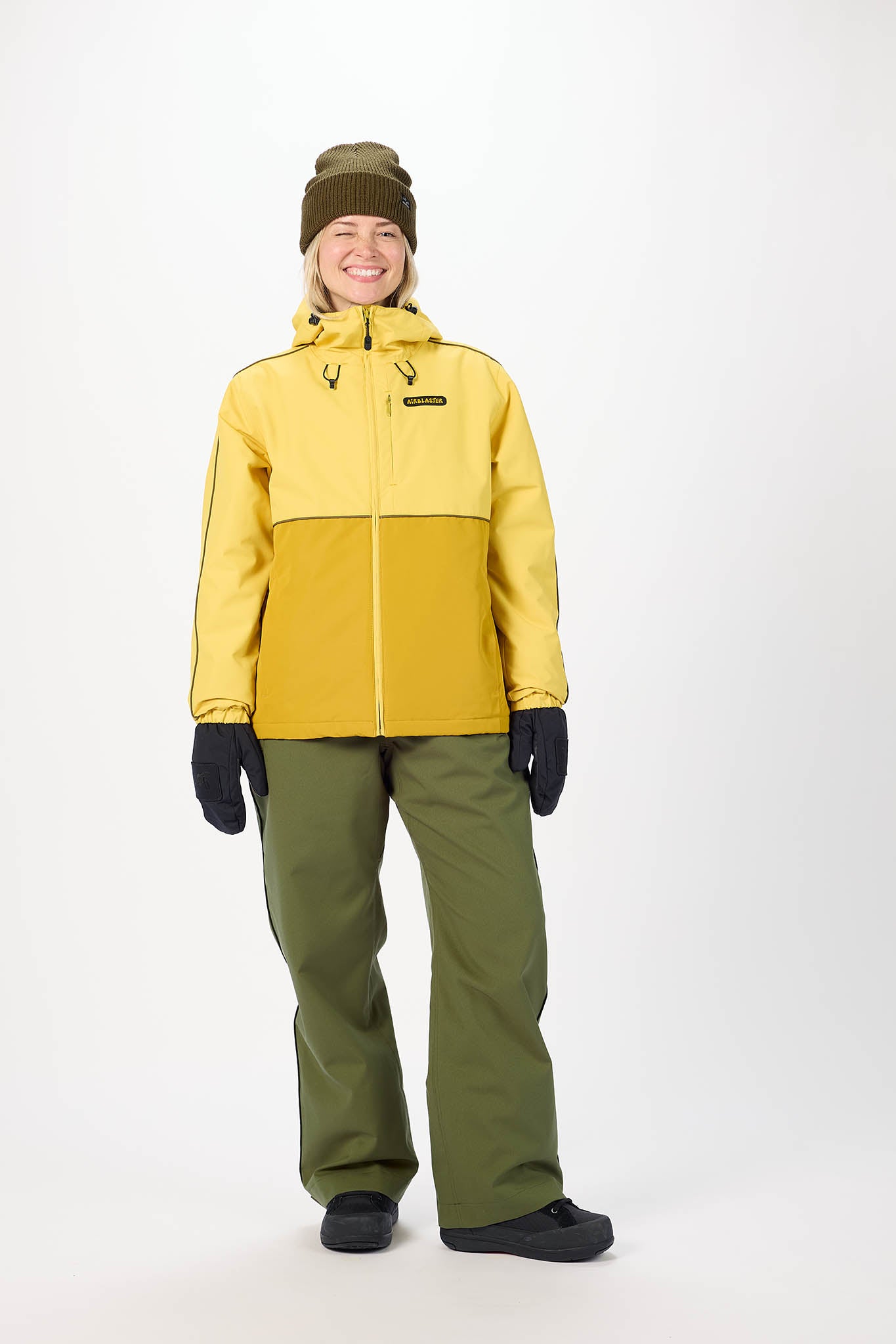 Person wearing a yellow and green winter jacket with pants on a white background