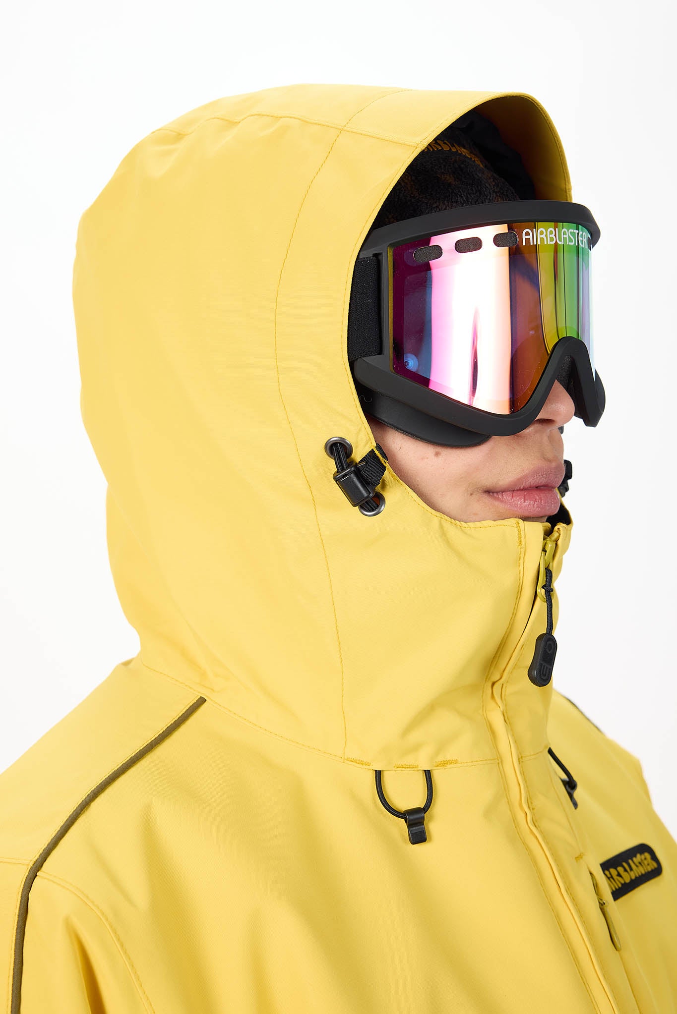 Person wearing a yellow snow jacket and goggles with a white background