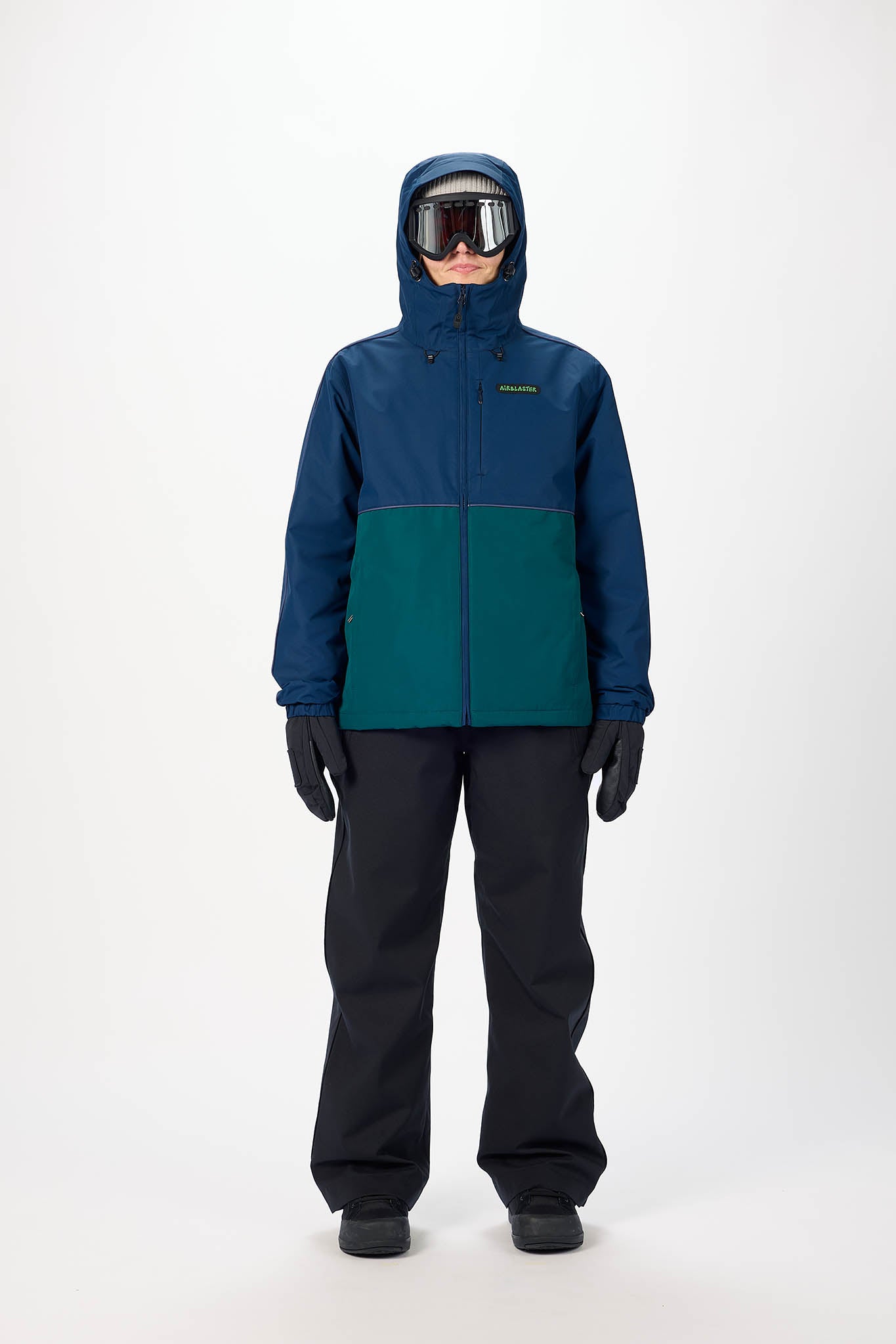 Person wearing a blue and green snow jacket with black pants on a white background