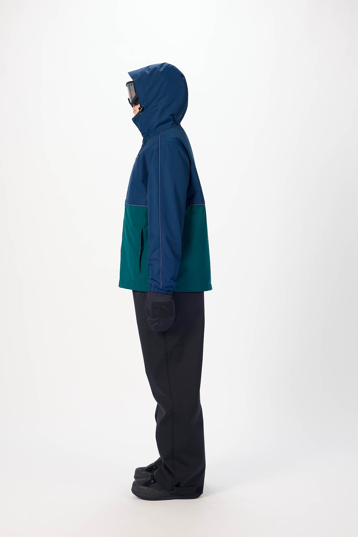Person wearing a blue and green jacket with a hood on a white background