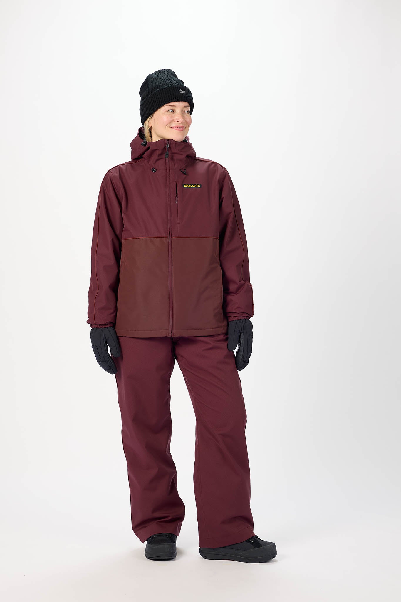 Person wearing a maroon snowsuit with a hood on a white background
