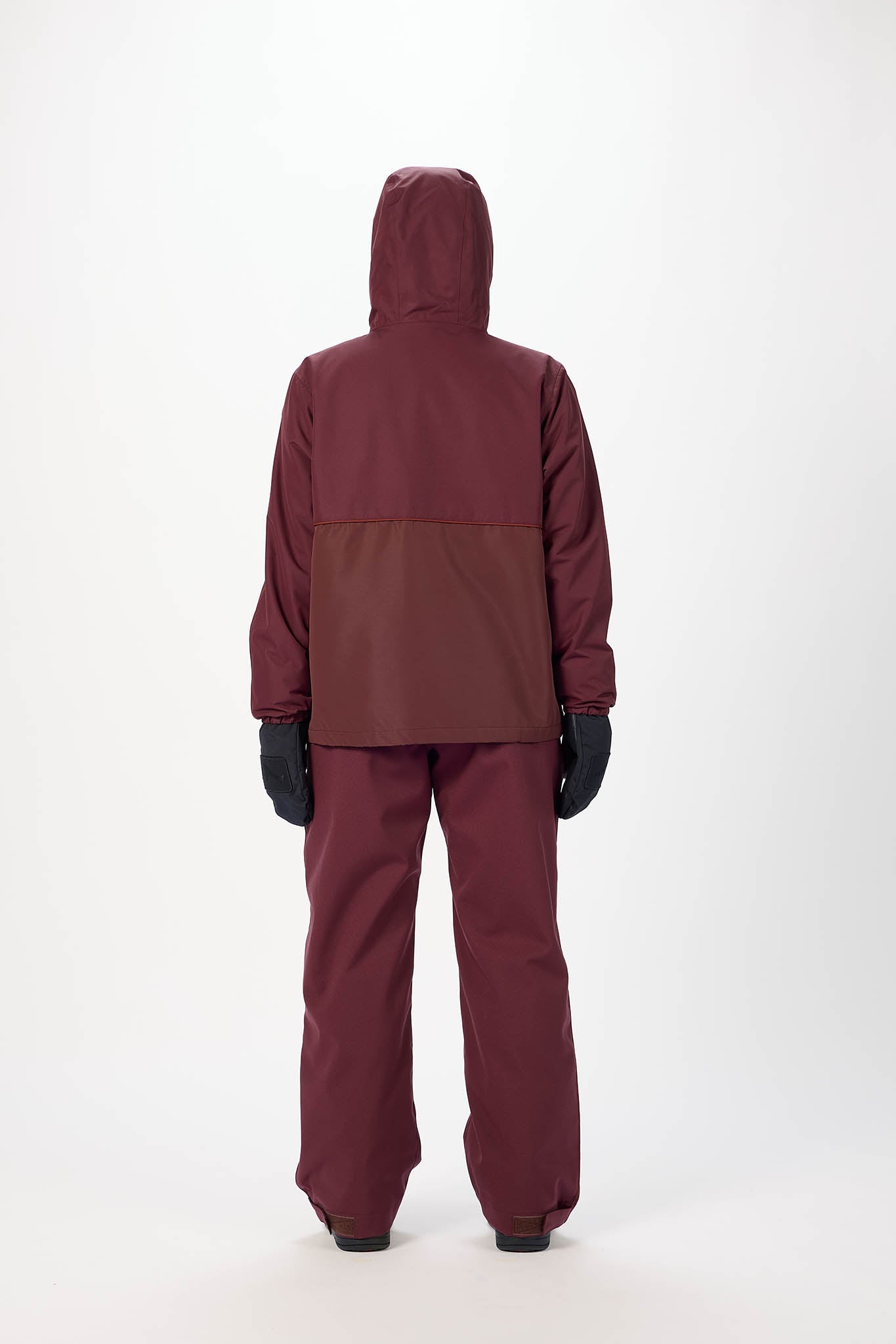 Person wearing a maroon raincoat and pants with black gloves on a white background