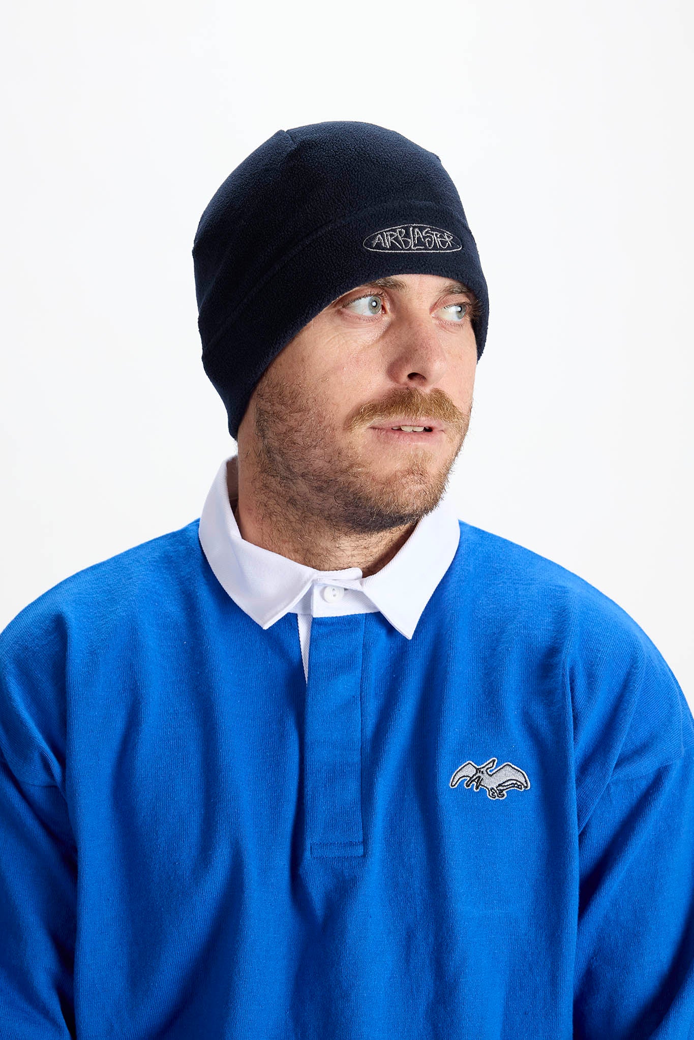 Man wearing a blue shirt and black beanie with a logo on a white background