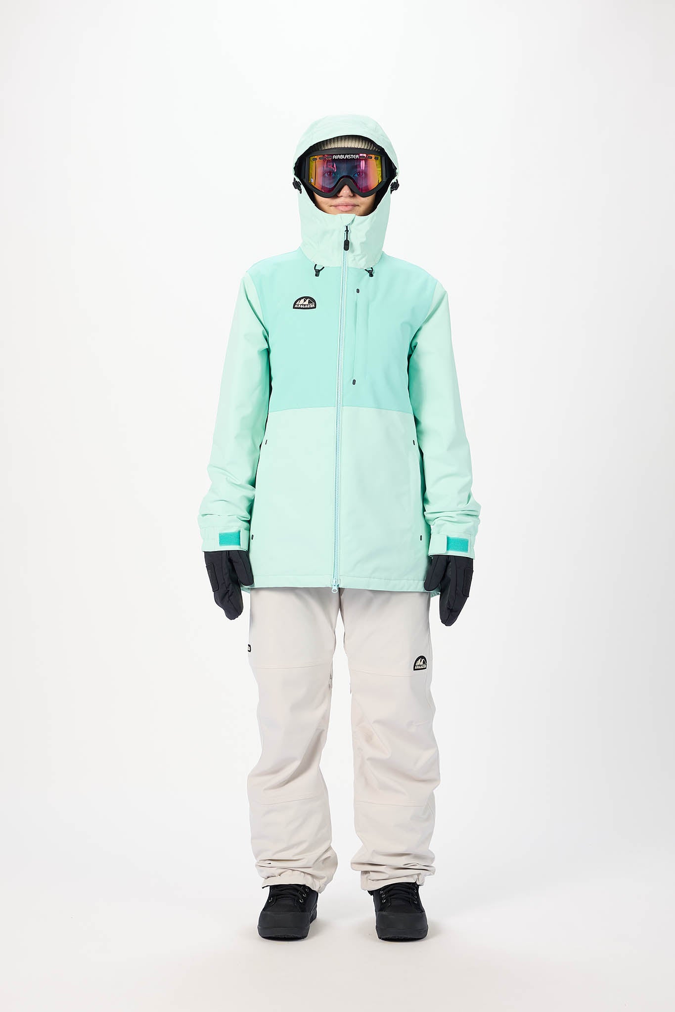 Person wearing a light blue snow jacket and pants with goggles on a white background