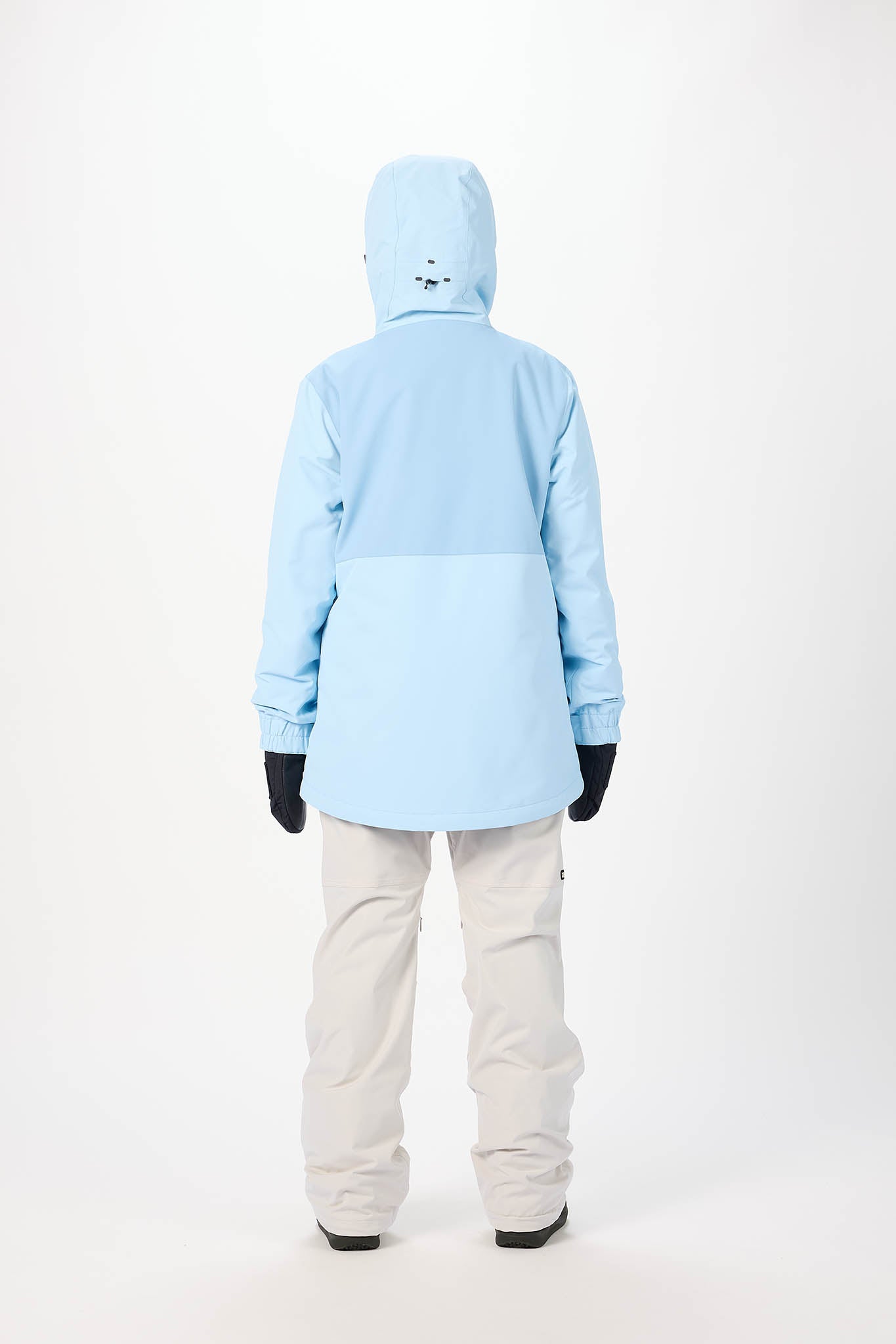 Person wearing a light blue snow jacket and white pants on a white background