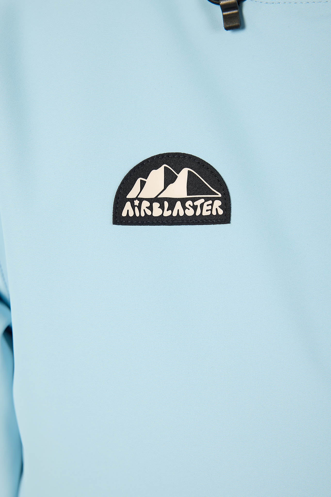 Close-up of a light blue jacket with an 'Airblaster' logo on a light blue background