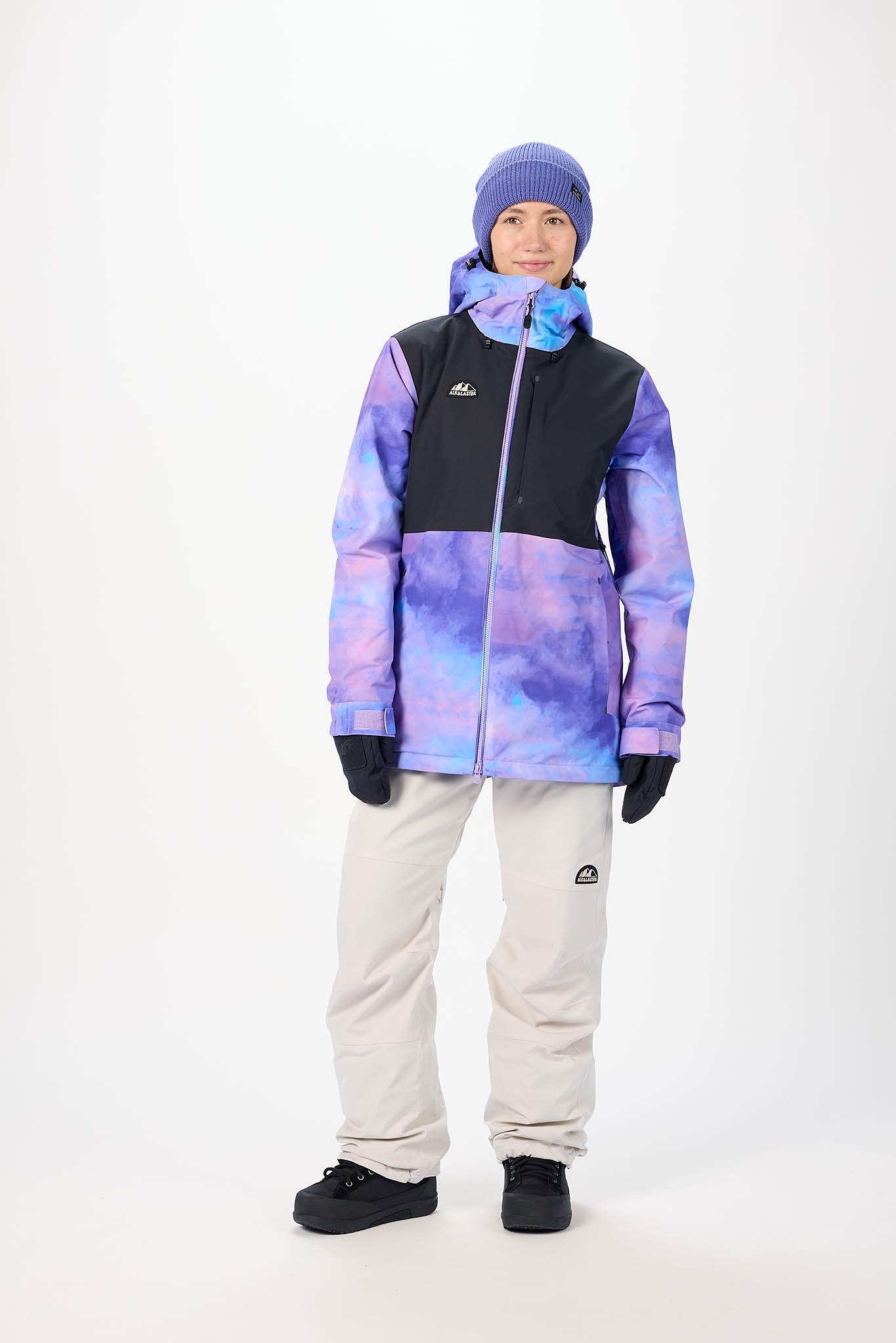 Person wearing a colorful jacket, pants, and beanie on a white background