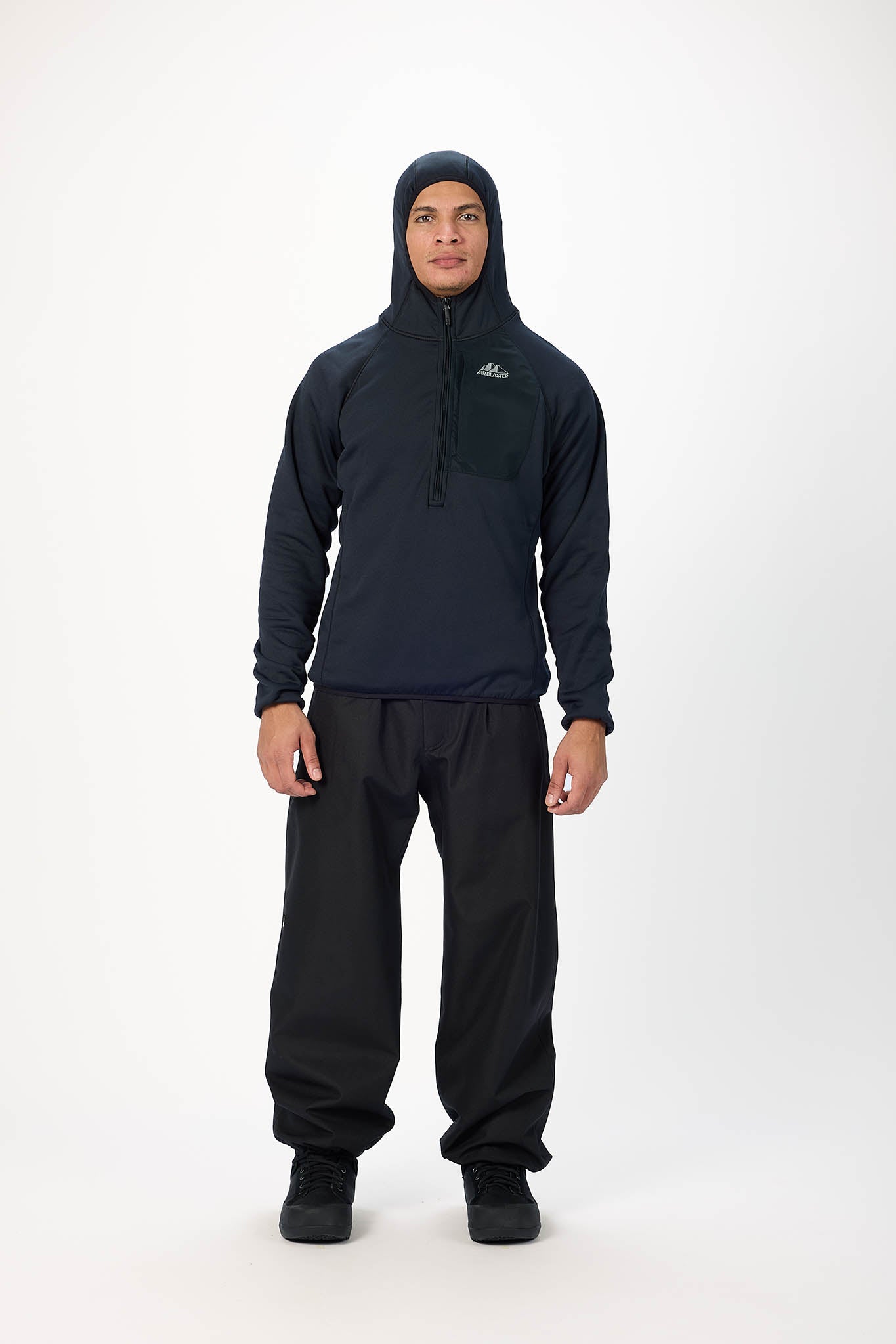 A man modeling a dark navy quarter-zip hooded fleece pullover and matching dark pants against a plain white studio background.