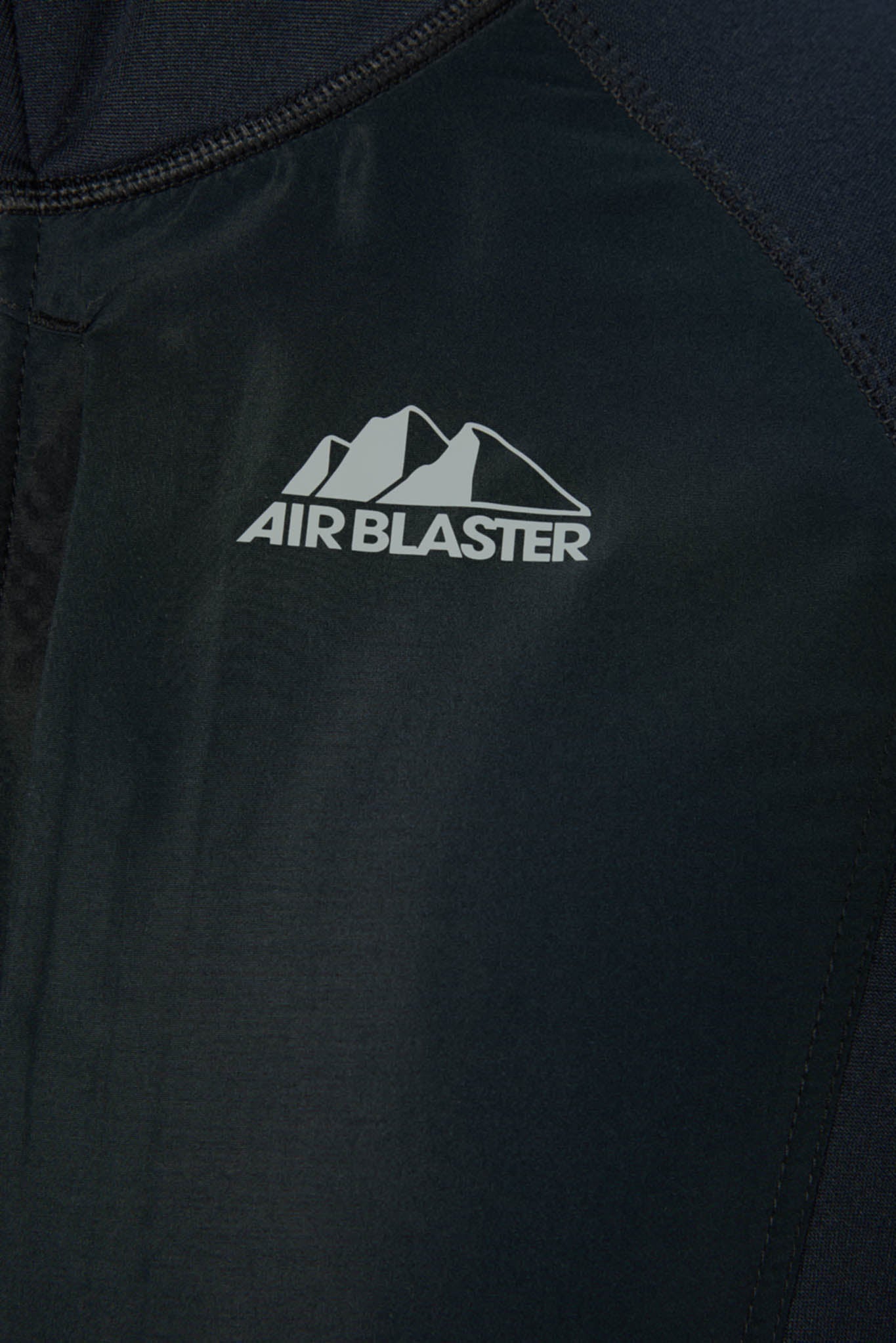 Close-up of a dark navy or black jacket fabric with a white Air Blaster logo and mountain graphic on the chest.