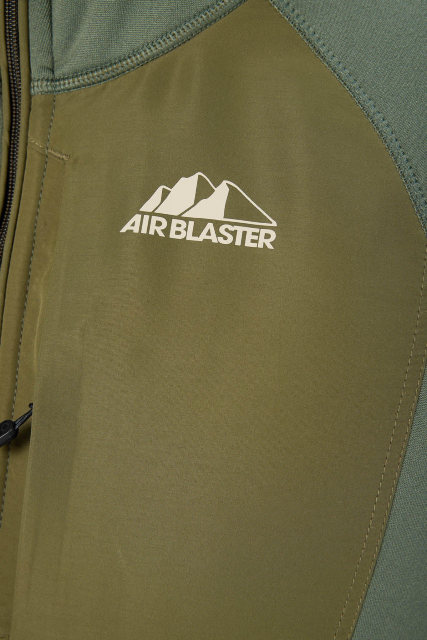 Close-up of an olive green zippered jacket with a white Air Blaster logo featuring a mountain graphic on the chest.