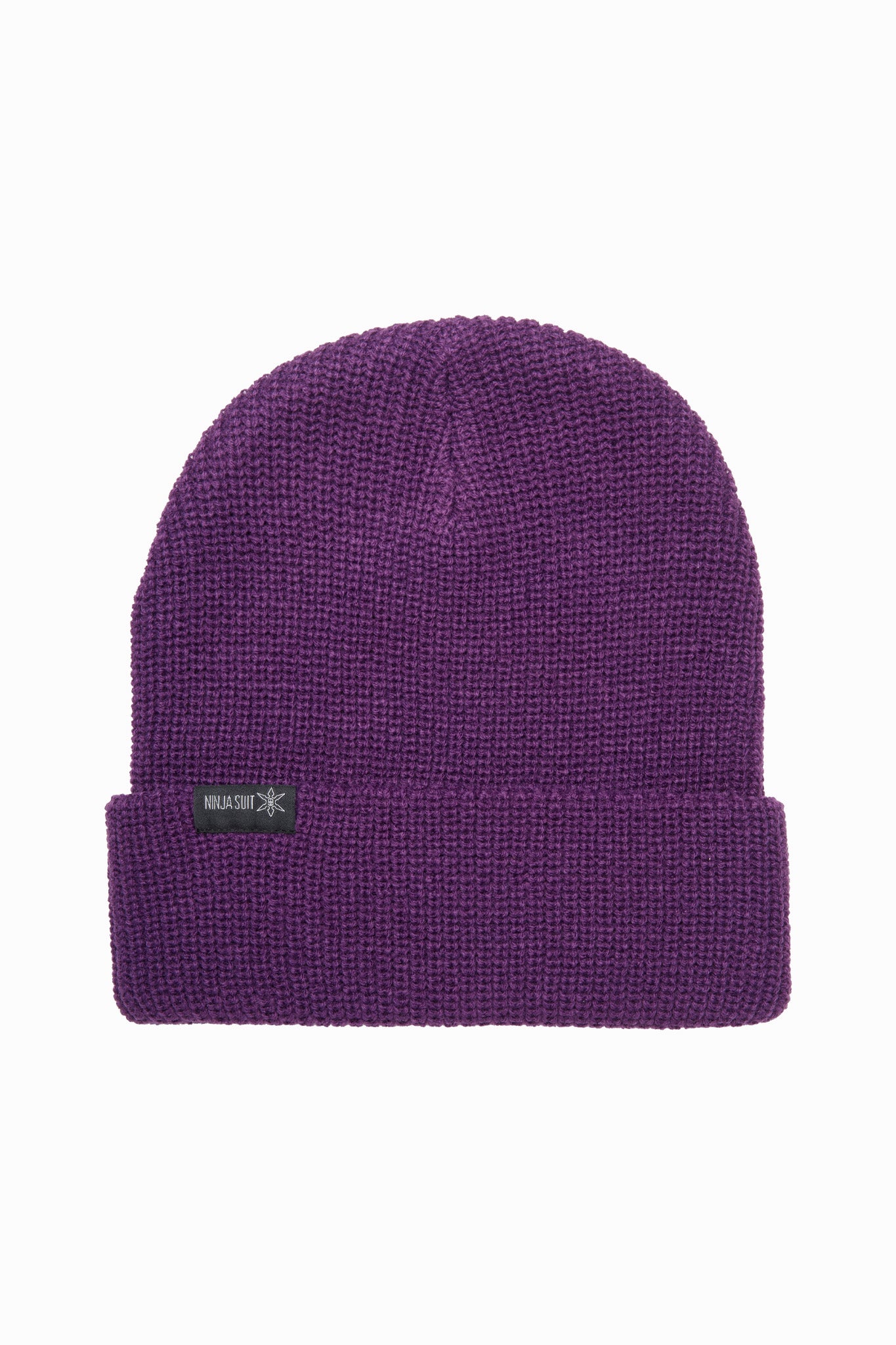 A purple knit beanie hat with a folded cuff and a small black brand patch on the front, shown against a plain white background.