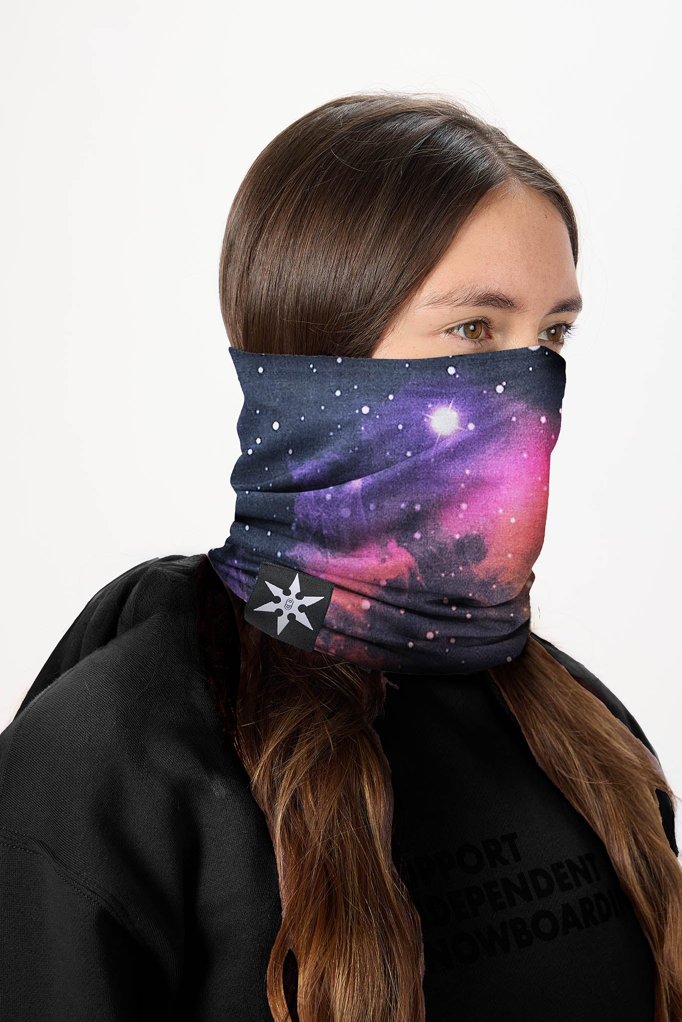 A woman wearing a galaxy-print neck gaiter mask, shown in profile against a plain white background.