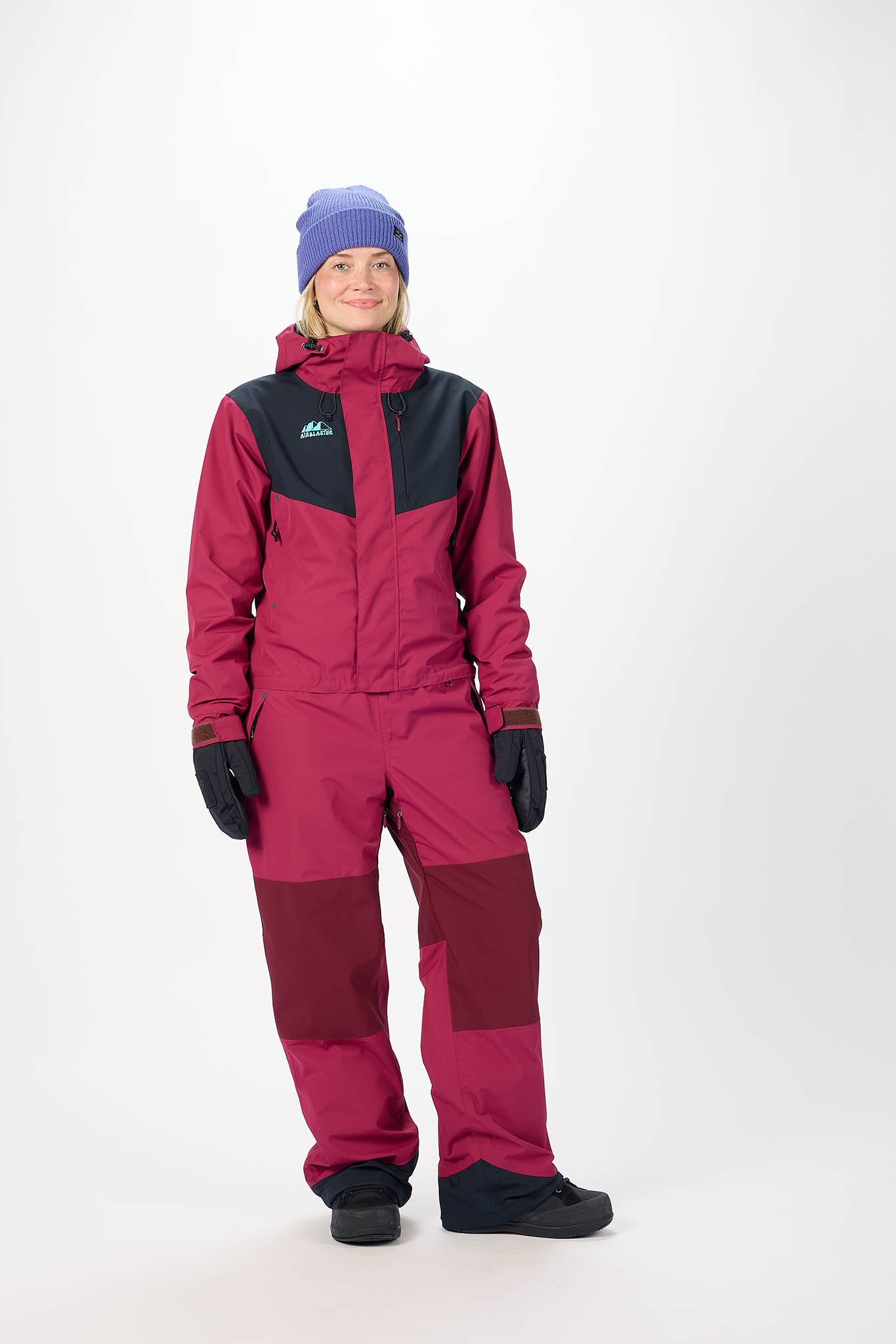 Person wearing a pink snowsuit with black accents on a white background