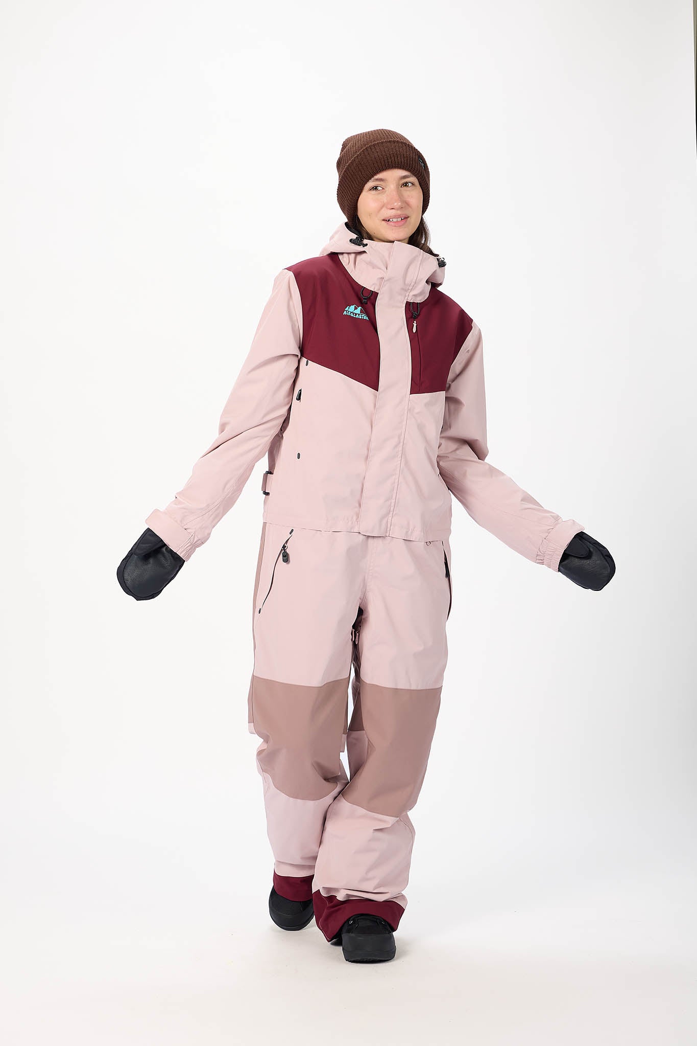 Person wearing a pink and maroon snowsuit with a white background